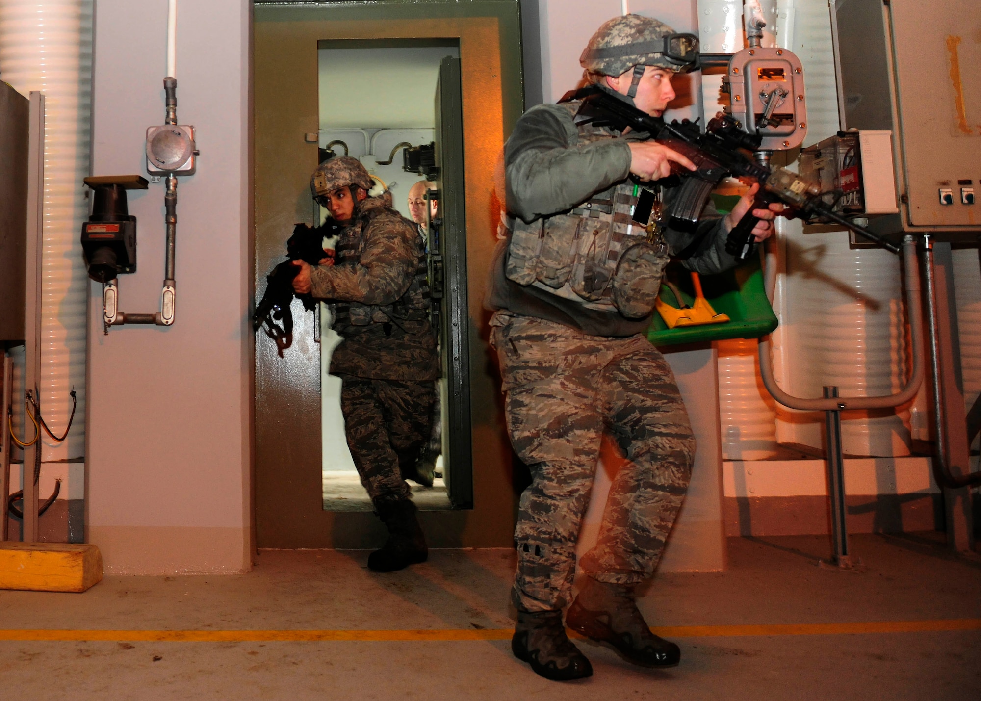 First Lieutenant Carlos Moralejo (left), 39th Security Forces Squadron flight commander, and Senior Airman Michael Dean, 39th SFS area supervisor, tactically enter an aircraft shelter during a base-wide exercise Jan. 28, 2015, at Incirlik Air Base, Turkey. As part of the exercise 39th SFS defenders responded to an active shooter inside of the shelter. (U.S. Air Force photo by Senior Airman Krystal Ardrey/Released)