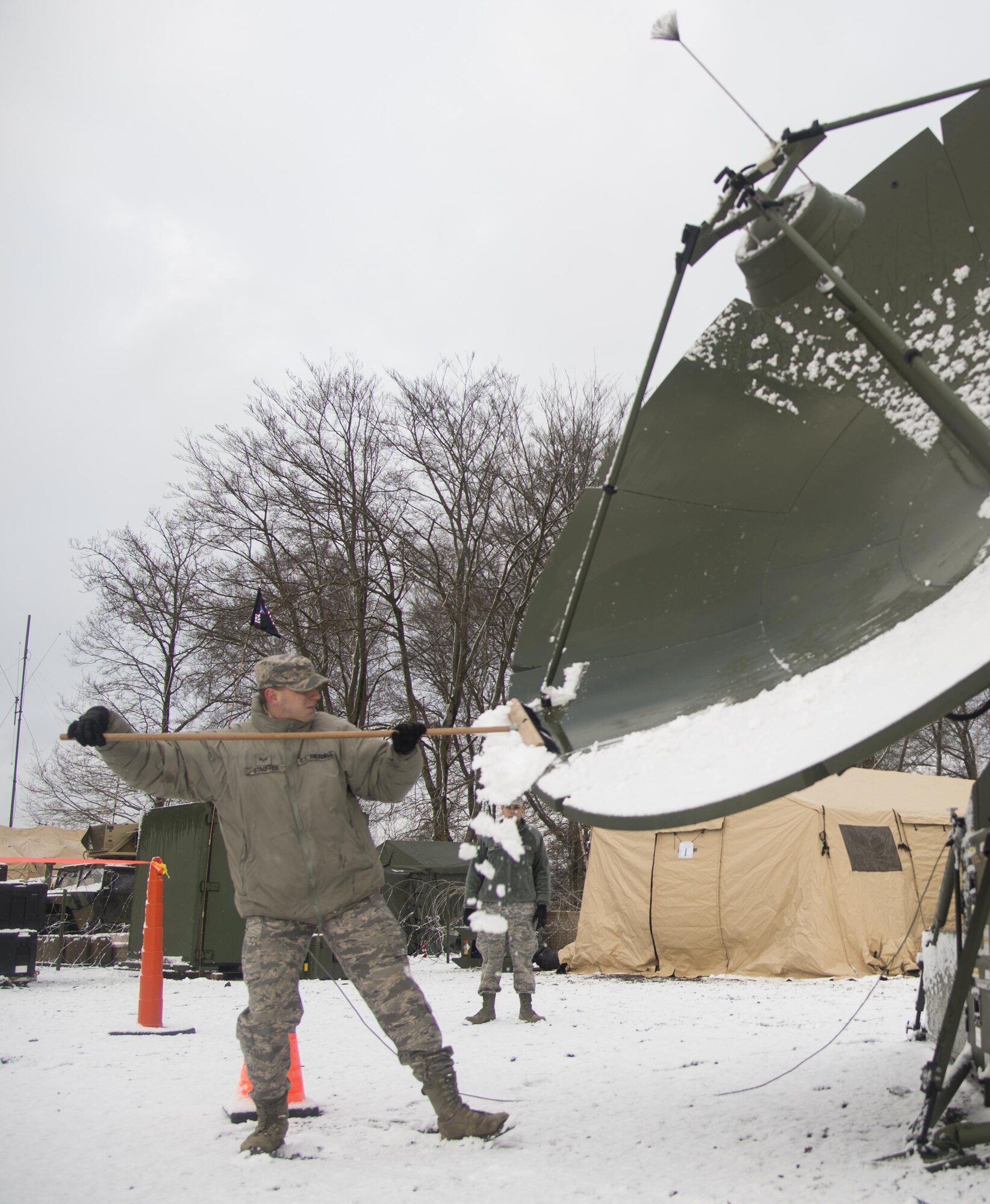 Senior Airman Erik Stauffer, 1st Combat Communications Squadron transmissions systems technician, cleans snow off of a satellite during exercise Juniper Thunder Jan. 30, 2015, at Ramstein Air Base, Germany. Juniper Thunder aimed to help the interoperability between Air Force and Army combat communications systems. (U.S. Air Force photo/Senior Airman Jonathan Stefanko)