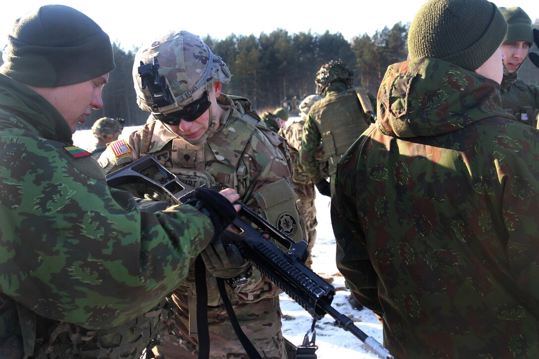 A Lithuanian soldier, left, explains his weapons operation to a U.S. soldier during a training exercise in Rukla, Lithuania Feb. 2, 2015.