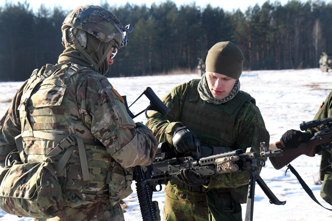 A U.s. Soldier, Left, Explains His Weapons Operation To A Lithuanian 