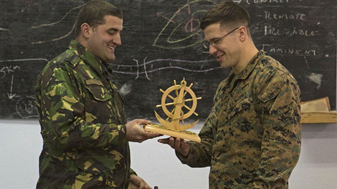 Major Claudiuv Vison presents the Marines with a plaque that symbolizes their naval heritage, thanking them for the workshop, Jan. 29. This three-day workshop, with the only battalion of Marines in Romania, covered tactics and troop-leading procedures and how the U.S. Marine Corps utilizes their noncommissioned officers in squad-sized elements. (USMC photo by Lance Cpl. Ashton C. Buckingham)