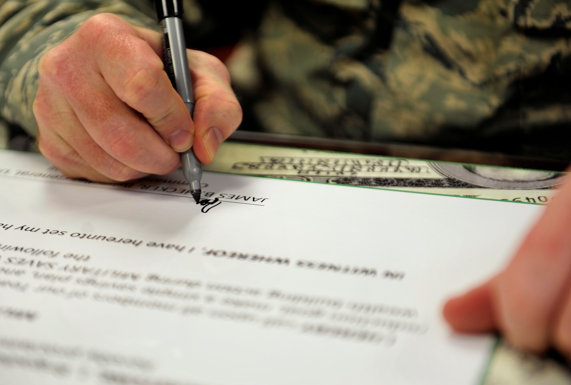 U.S. Air Force Brig. Gen. James Hecker, 18th Wing commander, signs the Military Saves Week proclamation board on Kadena Air Base, Japan, Feb. 4, 2015. The Military Saves campaign encourages military families to save money every month. It is also held to convince leaders and organizations to be aggressive in promoting automatic savings. (U.S. Air Force photo by Naoto Anazawa)