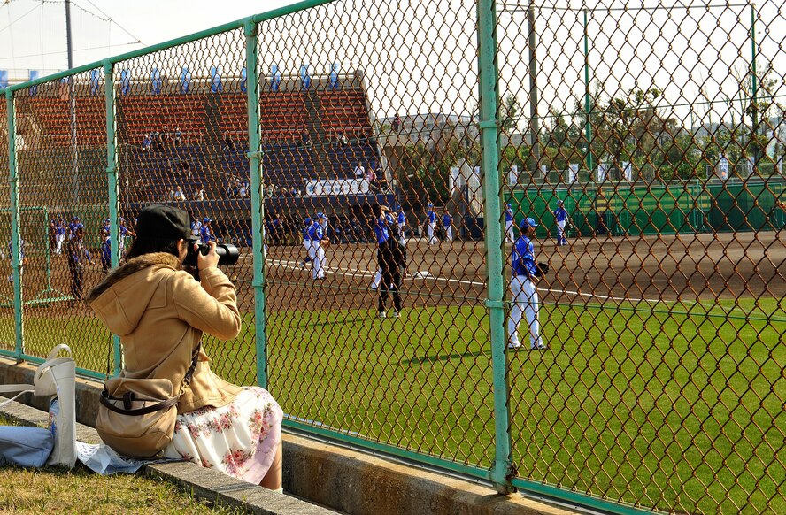 A fan takes a photograph of professional baseball players practicing during spring training camp at the Ginowan Municipal Baseball Stadium, Okinawa, Japan, Feb. 2, 2015. Professional baseball camp allows fans the opportunity to see their favorite players up close and possibly to speak with them directly. Also, it is a good chance to get photographs and autographs. (U.S. Air Force photo by Naoto Anazawa)