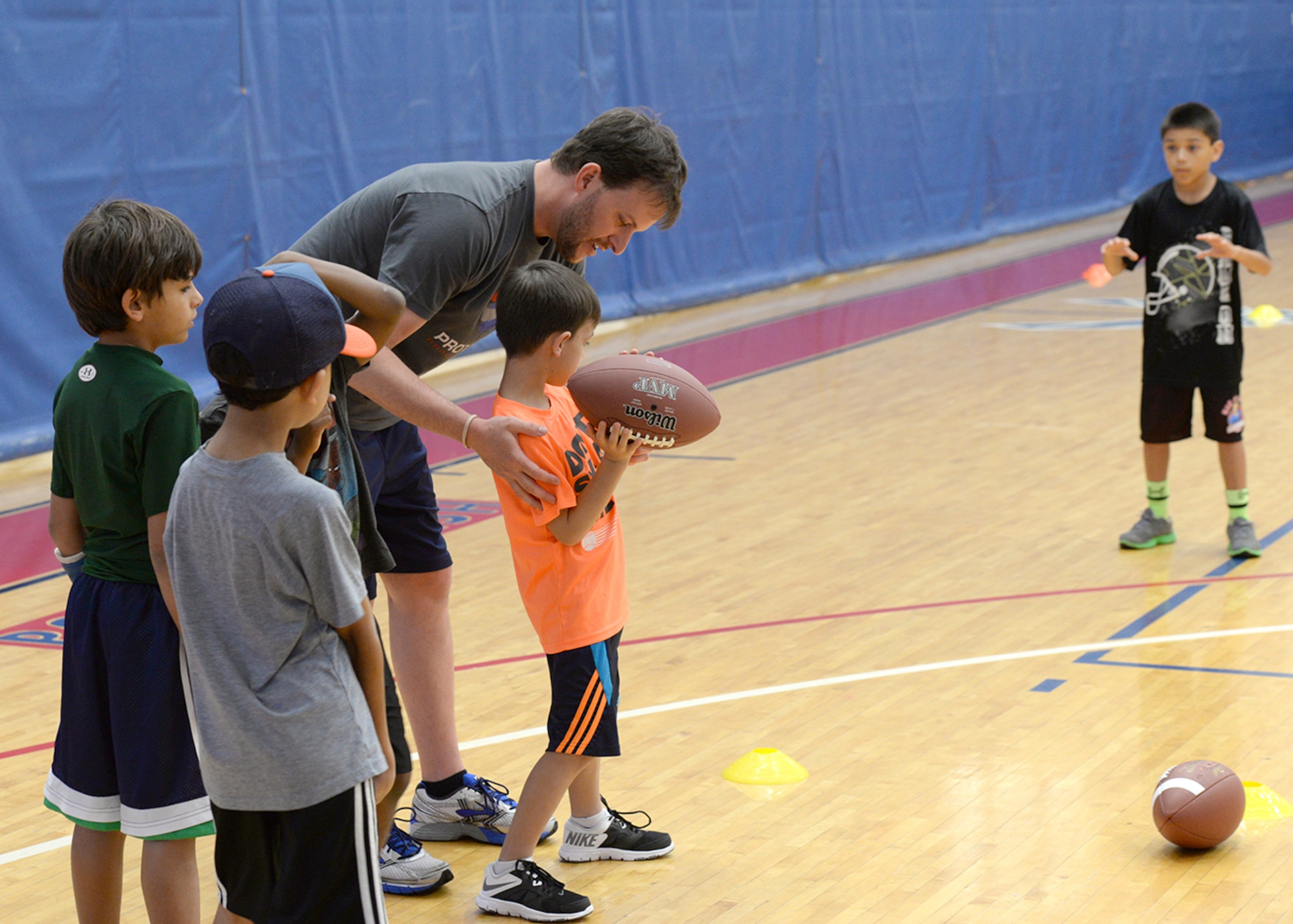 Pete Nelson, also known as “T-RAC,” mascot for the National Football League’s Tennessee Titans, helps Team Andersen members through passing drills during a clinic Feb. 1, 2015 at the Coral Reef Fitness Center at Andersen Air Force Base, Guam. Nelson joined with several other NFL players, cheerleaders and mascots as part of the Armed Forces Entertainment Guam Super Bowl Tour that allowed the NFL visitors to meet with island military members and their families (U.S. Air Force photo by Tech. Sgt. Zachary Wilson)