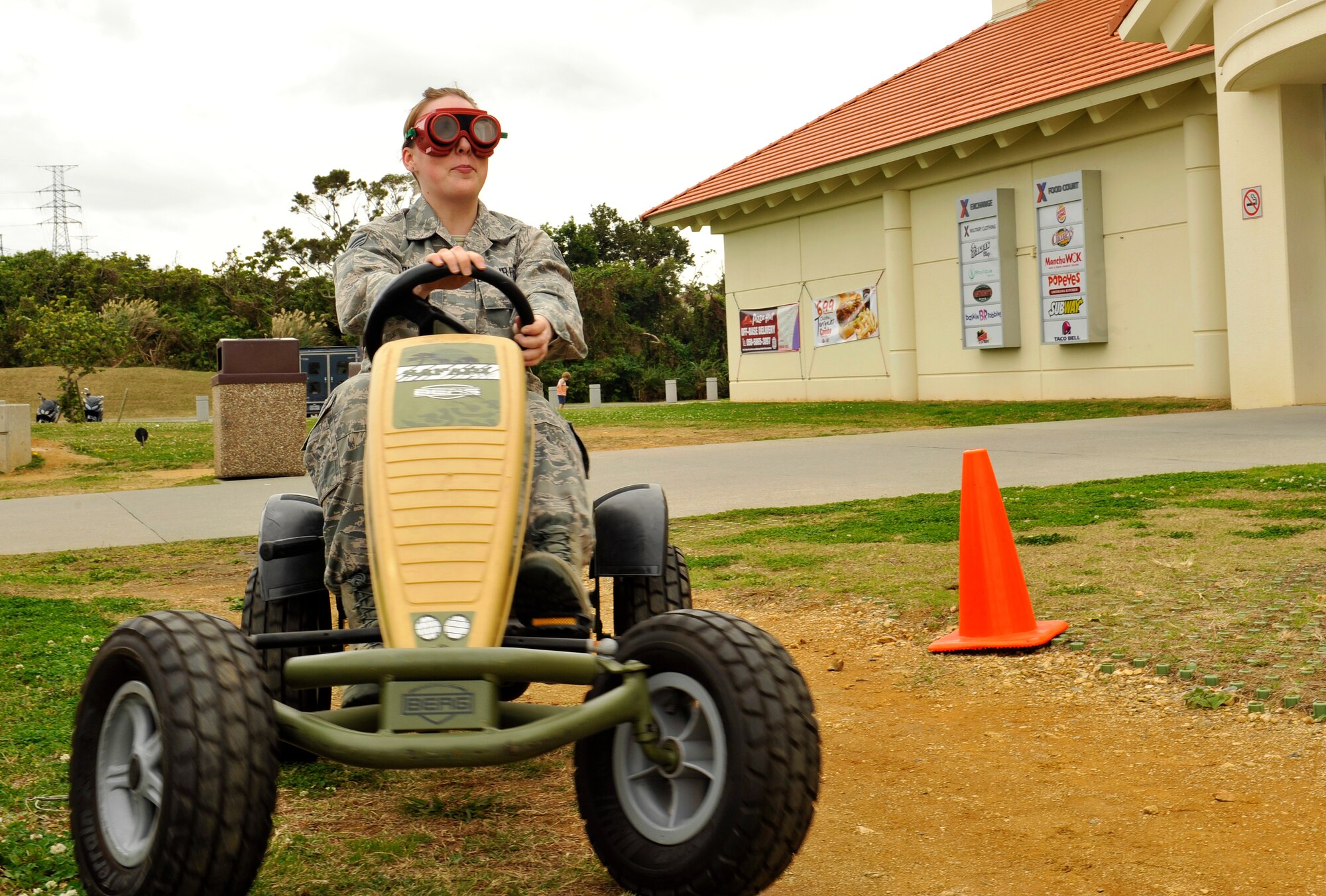 U.S. Air Force Senior Airman Macey Bonham, 18th Dental Squadron dental lab technician, drives a "Drink Buster" bike around cones while wearing goggles that simulate intoxication during a health fair at the Exchange on Kadena Air Base, Japan, Feb. 3, 2015. Military service members, Department of Defense civilians and contractors participated in the health fair, which included information booths, demonstrations and a "Drink Buster" bike. (U.S. Air Force photo by Naoto Anazawa)