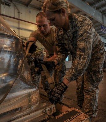 U.S. Air Force Tech. Sgt. George Welliver (left), 72nd Aerial Port Squadron cargo journeyman, shows Capt. Kelly Womble, 15th Maintenance Squadron Maintenance Flight commander, tighten procedures for belly bands during a demonstration of palette buildup at the 735th Air Mobility Squadron Aerial Port at Joint Base Pearl Harbor-Hickam, Hawaii, Jan. 29, 2015. (U.S. Air Force photo by Tech. Sgt. Terri Paden/Released)