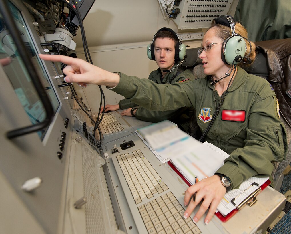 A U.S. Air Force aircrew member with the 461st Air Control Wing, right, points out details about the operator work station to U.S. Navy Lt. j.g. John Duffner, a naval flight officer with Carrier Airborne Early Warning Squadron 126, during a mission aboard an E-8C Joint STARS, Robins Air Force Base, Ga., Jan. 30, 2015. Duffner, from Naval Station Norfolk, flew two missions with Team JSTARS as a liaison officer to learn more about the capabilities of the Joint STARS weapon system and share his experience with his carrier group. During the Composite Training Unit Exercise, JSTARS used their unique Command and Control, Intelligence, Surveillance, Reconnaissance and Battle Management capabilities to provide the warfare commander long-range, air-to-surface wide area surveillance to track ground and maritime targets in all weather conditions. Aircrew members from the 116th Air Control Wing, Georgia Air National Guard, Team JSTARS host unit, also flew on board the 30-person crew (U.S. Air National Guard photo by Master Sgt. Roger Parsons/Released) (Portions of the photo have been blurred and JSTARS crewmember name withheld for security purposes)