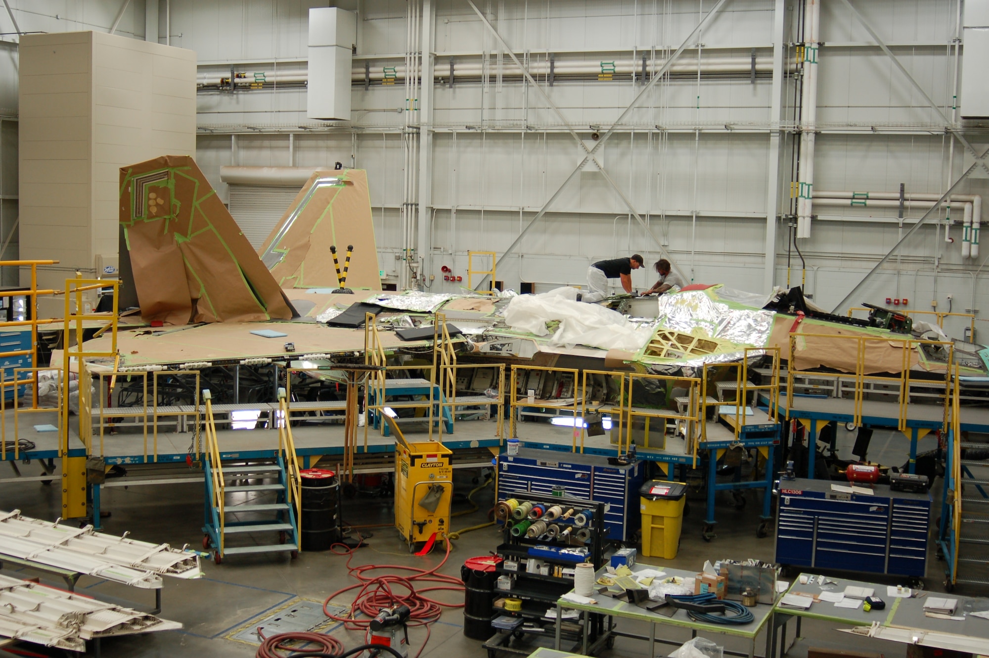 Fuel mechanics with the 574th Aircraft Maintenance Squadron inspect fuel panels on an F-22 Raptor, brought to the Ogden Air Logistics Complex for scheduled depot maintenance. During maintenance, the aircraft is covered with paper and cardboard to protect its low-observable coating. The award- winning 574th AMXS F-22 Raptor Depot Maintenance Team provides scheduled and unscheduled depot-level maintenance for the Air Force's fleet of 187 F-22 Raptor aircraft. The F-22 is the world's most technologically advanced, low observable air superiority fighter in active service today. (Air Force photo by Bill Orndorff)