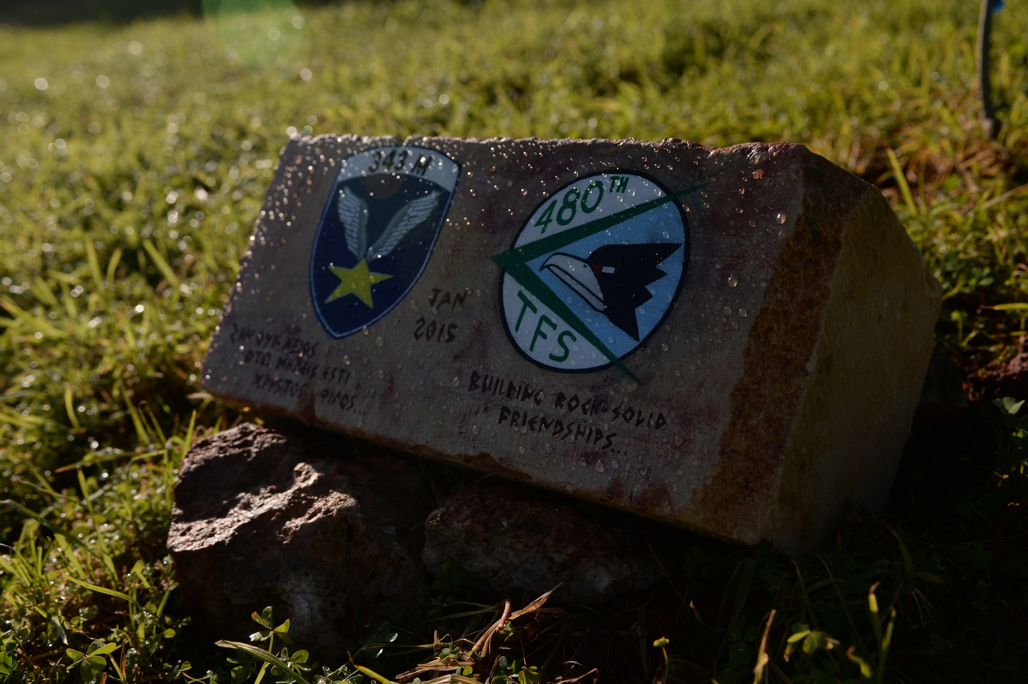 A commemorative stone marking the bilateral friendship between the Hellenic air force's 343rd Fighter Squadron and the U.S. Air Force's 480th Expeditionary Fighter Squadron rests before an olive tree outside the 343rd FS's headquarters at Souda Bay, Greece, Feb. 3, 2015.  The squadron's Airmen planted the tree as a symbol of the partnership between the two countries. (U.S. Air Force photo by Staff Sgt. Joe W. McFadden/Released)