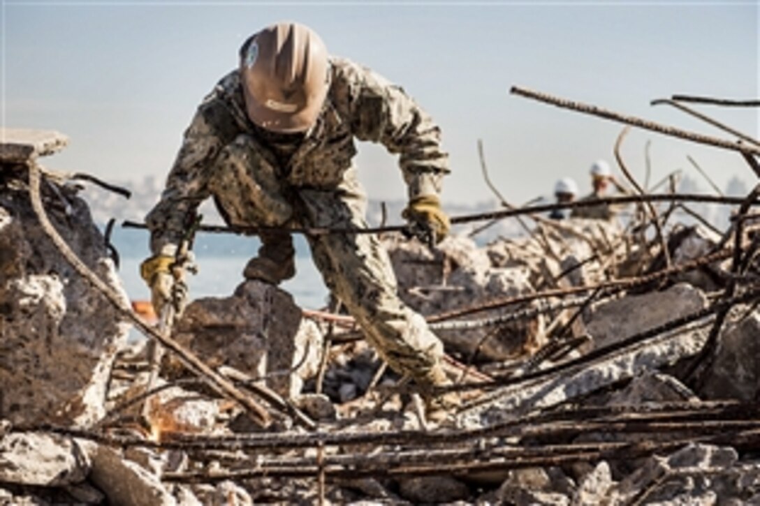 Navy Petty Officer 1st Class Honer Villanueva cuts rebar beams with an oxygen acetylene torch during a seaplane ramp construction project in Coronado, Calif., Feb. 03, 2015. Villanueva is a steelworker assigned to Naval Mobile Construction Battalion 3.