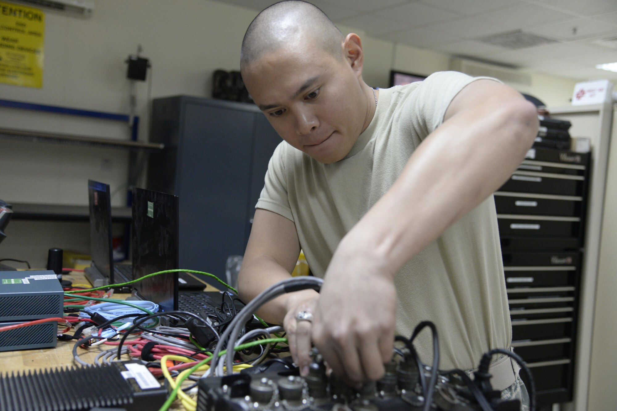 Airman 1st Class Ryan, radio frequency transmission technician, connects power cables for a non-secure internet protocol router to a power strip at an undisclosed location in Southwest Asia Jan 28, 2015. The radio frequency team will soon take part in replacing all the LMR’s on base, which includes over 1,000 handhelds, 80 base stations and 50 mobile systems. Ryan is currently deployed from Nellis Air Force Base, Nev., and is a native of Las Vegas, Nev. (U.S. Air Force photo/Tech. Sgt. Marie Brown)