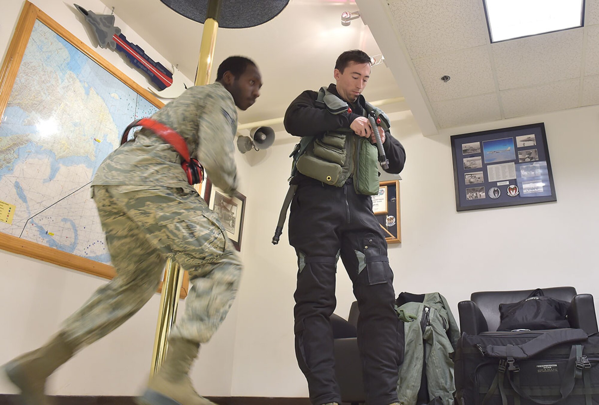 Senior Airman Stephen Teamer, assigned to the 3rd Aircraft Maintenance Squadron, rushes to an aircraft hangar as Air Force 1st Lt. Daniel Harp, an F-22 Raptor pilot assigned to the 525th Fighter Squadron, suits up at the Combat Alert Center on Joint Base Elmendorf-Richardson Jan. 23. Within minutes of an alert, Airmen in the CAC spring into action and launch F-22 Raptors to intercept aircraft entering U.S. airspace or potential airborne threats. (U.S. Air Force photo/Justin Connaher)