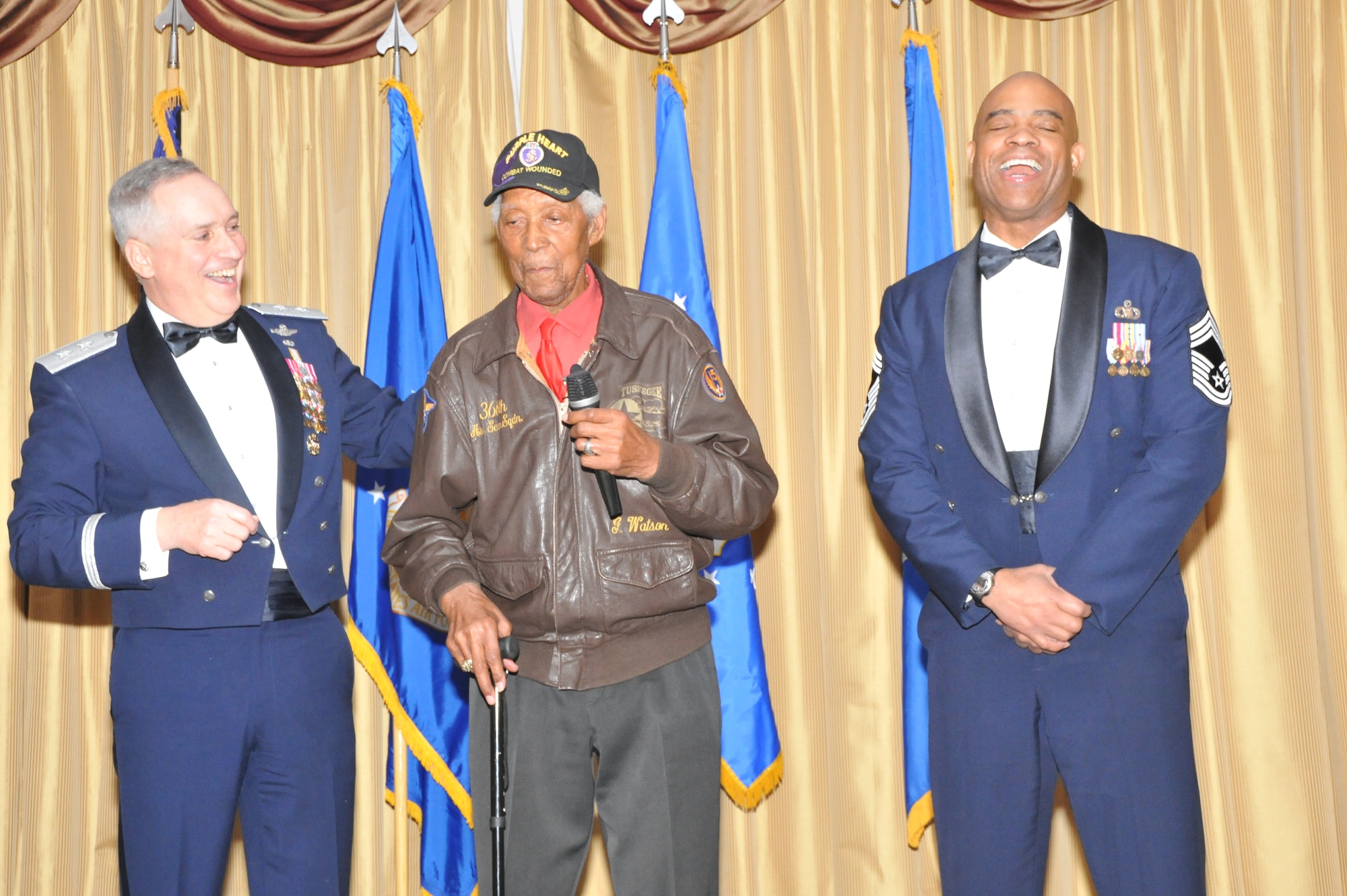 Retired Tech. Sgt. George Watson Sr., an original Tuskegee Airmen, shares a laugh on stage with Maj. Gen. Rick Martin, U.S. Air Force Expeditionary Center commander, and Chief Master Sgt. Vincent Burrell, U.S. Air Force Expeditionary Operations School command chief, at Joint Base McGuire-Dix-Lakehurst, N.J., Feb. 4, 2015. Watson was the guest speaker at the USAF EC Annual Awards Ceremony. (US Air Force photo/ Brad Camara)