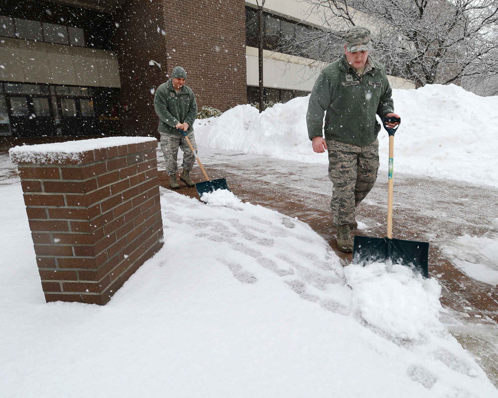 Senior Airman John D. Egbert III, 66th Force Support Squadron outbound assignments technician, and Master Sgt. Nicholas A. Souza, 66th Comptroller Squadron first sergeant, remove snow from outside the Brown Building, Feb. 5. This was the third time snow has fallen on the base in less than two weeks. (U.S. Air Force photo by Jerry Saslav) 