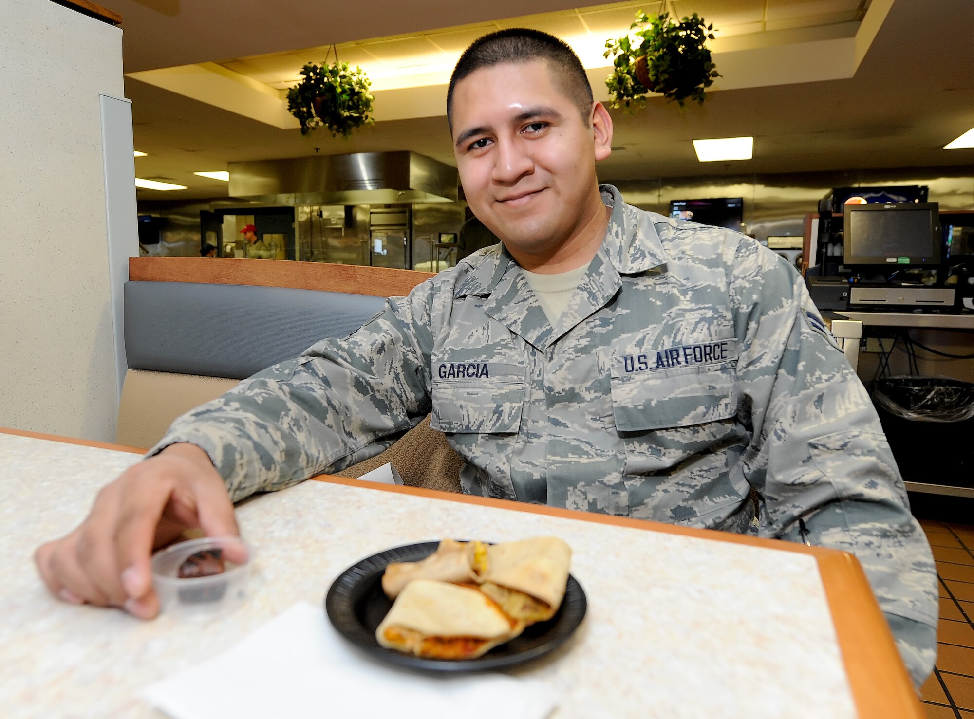 Airman 1st Class Jose Garcia, 436th Force Support Squadron career development section, smiles after sitting down in the Patterson Dining Facility with samples of food while attending the Food Forum on Feb. 4, 2014, at Dover Air Force Base, Del. Many airmen who live in the dorms on Dover AFB were in attendance to give input and receive information about how the upcoming Food Transformation Initiative will impact them while the dining facility is closed for approximately six months. (U.S. Air Force photo/Greg L. Davis)