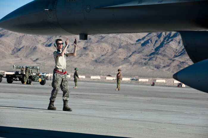 Airman 1st Class Andrew Galeener, an F-16 Fighting Falcon crew chief assigned to the 158th Fighter Wing, Burlington Air National Guard Base, Vt., marshalls an F-16 during Red Flag 15-1 at Nellis Air Force Base, Nev., Feb. 4, 2015. Red Flag provides a series of air combat scenarios designed to increase air and ground crew combat readiness and effectiveness. (U.S. Air Force photo by Senior Airman Thomas Spangler)