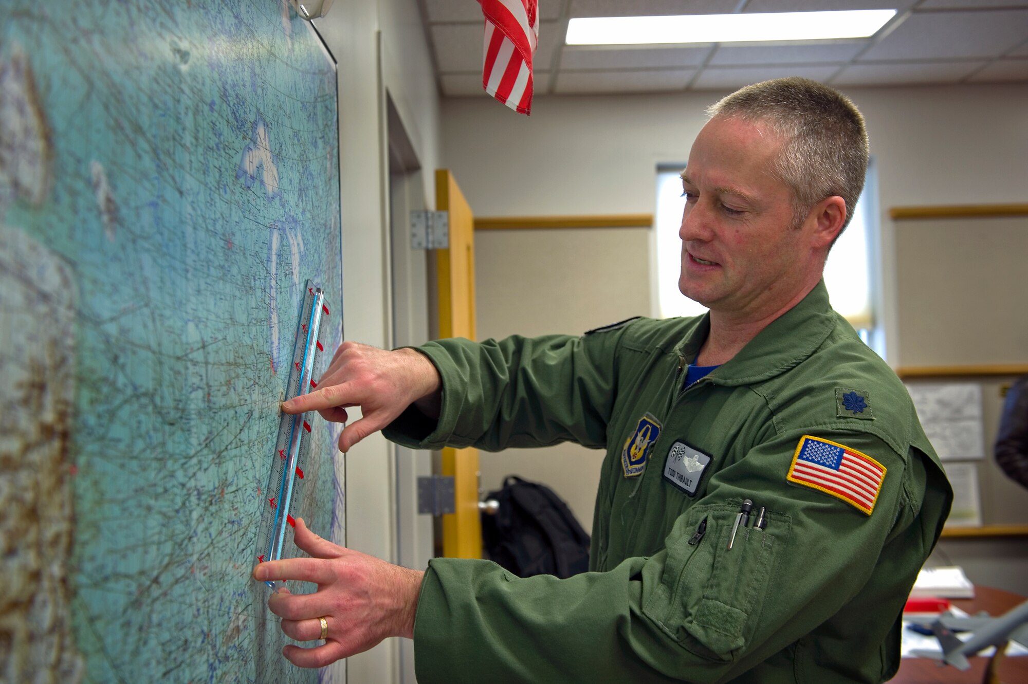 Lt. Col. Todd Thibault, 434th Operations Support Squadron chief of scheduling, points out one of several flight refueling tracks on a map of the United States at Grissom Air Reserve Base, Ind. Jan. 30, 2014. Schedulers with the 434th OSS coordinated nearly 1,300 successful missions here through their detailed planning efforts in 2014 alone. (U.S. Air Force photo/Tech. Sgt. Benjamin Mota)