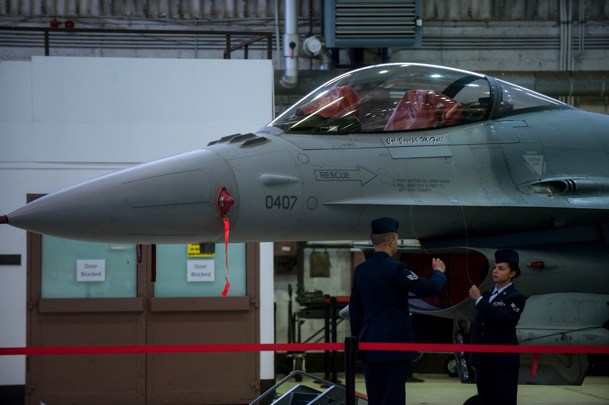 U.S. Air Force Staff Sgt. Juan Silver and Senior Airman Kimberly Szydlowski, both 52nd Aircraft Maintenance Squadron crew chiefs, unveil the name of Col. Joseph McFall, 52nd Fighter Wing commander, on the wing's flagship F-16 Fighting Falcon fighter aircraft during an assumption of command ceremony Feb. 5, 2015, in Hangar 1 at Spangdahlem Air Base, Germany. McFall assumed command of the wing after serving as commander of the 435th Air Ground Operations Wing at Ramstein Air Base, Germany. (U.S. Air Force photo by Senior Airman Rusty Frank/Released)