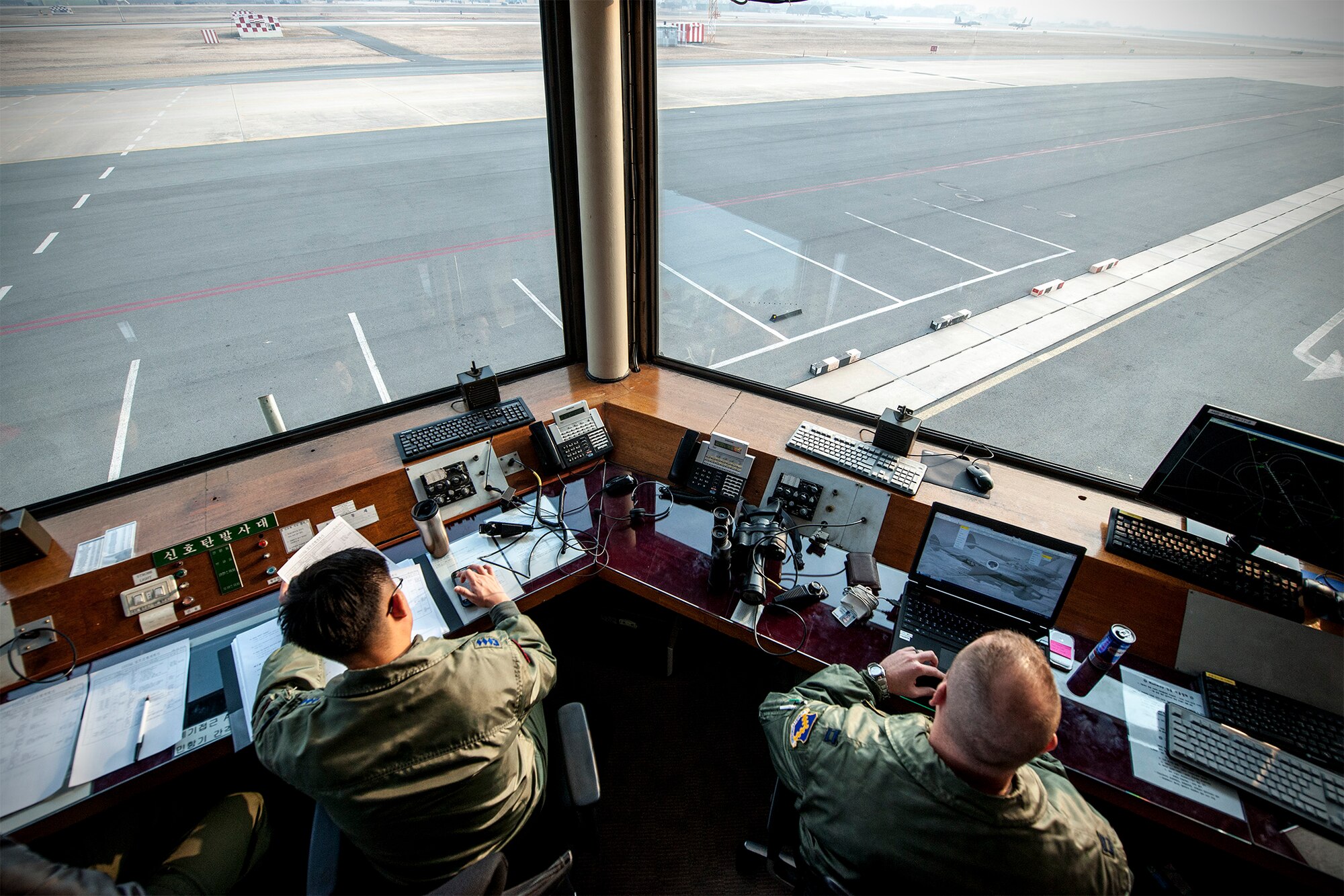 Capt. Justin Ankenbruck, 80th Fighter Squadron F-16 Fighting Falcon pilot, (right) and Capt. Sung Kwang Jang, 102nd Fighter Squadron F-15K Slam Eagle pilot, monitor sortie takeoffs from a runway control house during Exercise Buddy Wing 15-2 at Daegu Air Base, Republic of Korea, Feb. 5, 2015. During this iteration of Buddy Wing, Wolf Pack Airmen deployed to Daegu to trained alongside Airmen of the 11th Fighter Wing, learning how to operate as one force with dissimilar fighter aircraft. (U.S. Air Force photo by Senior Airman Katrina Heikkinen/Released)