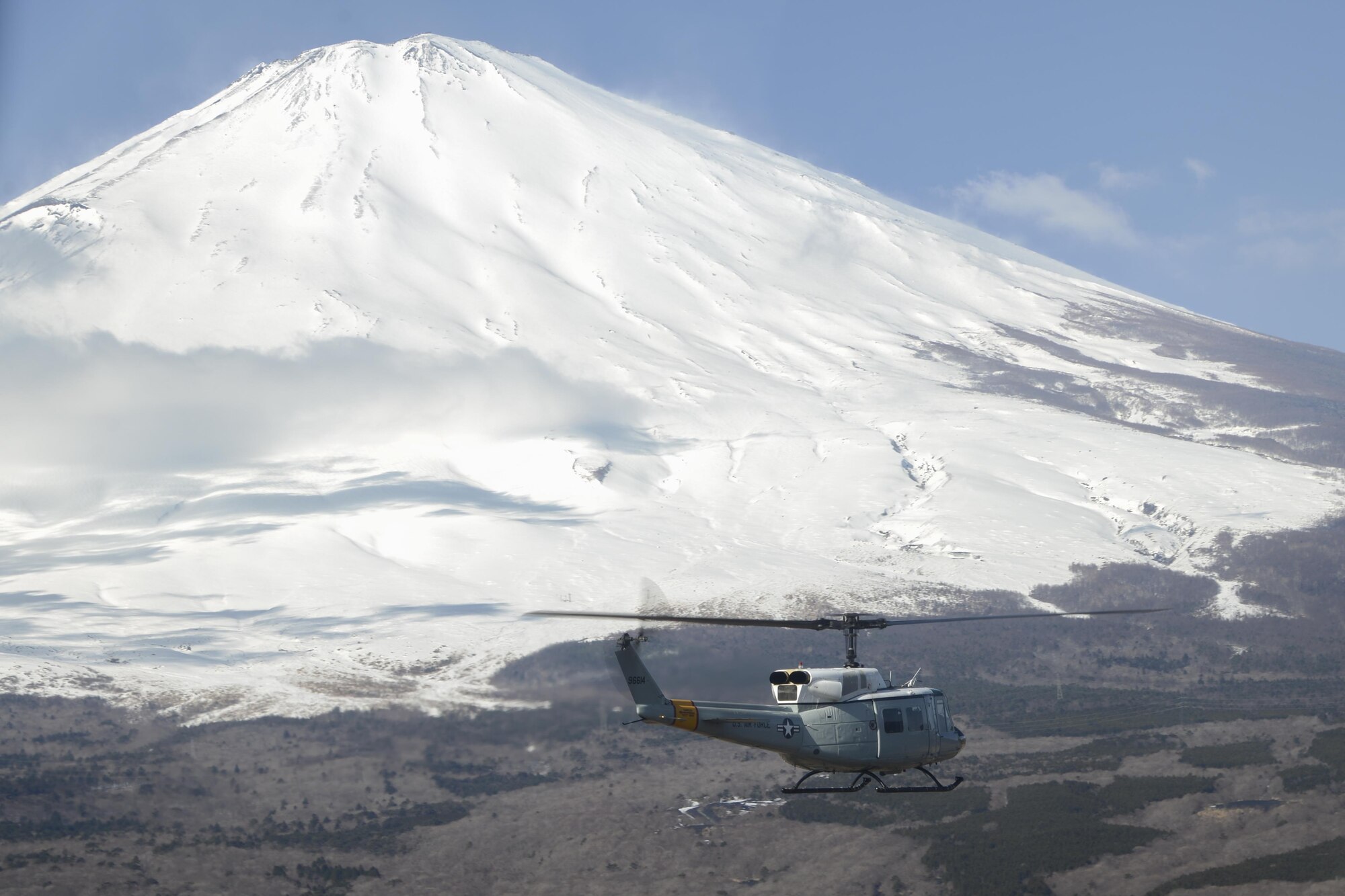 A UH-1 Huey helicopter flies toward Mt. Fuji during a bilateral training mission Jan. 29, 2015 near Tokyo, Japan. Two helicopters were used during the training mission where the pilots were able to practice formations, maneuvers and rescue tactics with Japan Ground Self-Defense Force members. (U.S. Air Force photo by Senior Airman Michael Washburn/Released)
