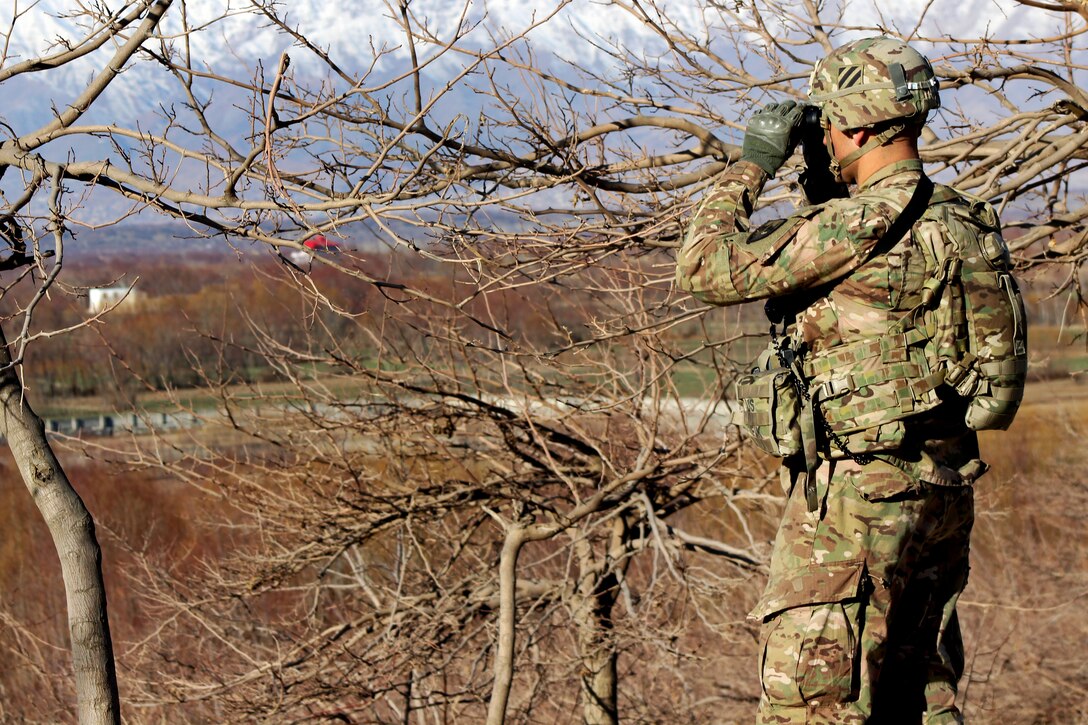 U.S. Army Sgt. 1st Class Jason Hickman scans the area using binoculars while providing security from behind a partial stone wall during a patrol with U.S., Czech and Afghan soldiers through a village in Parwan province, Afghanistan, Jan. 27, 2015. Hickman is assigned to the 3rd Infantry Division's 2nd Squadron, 3rd Cavalry Regiment. 