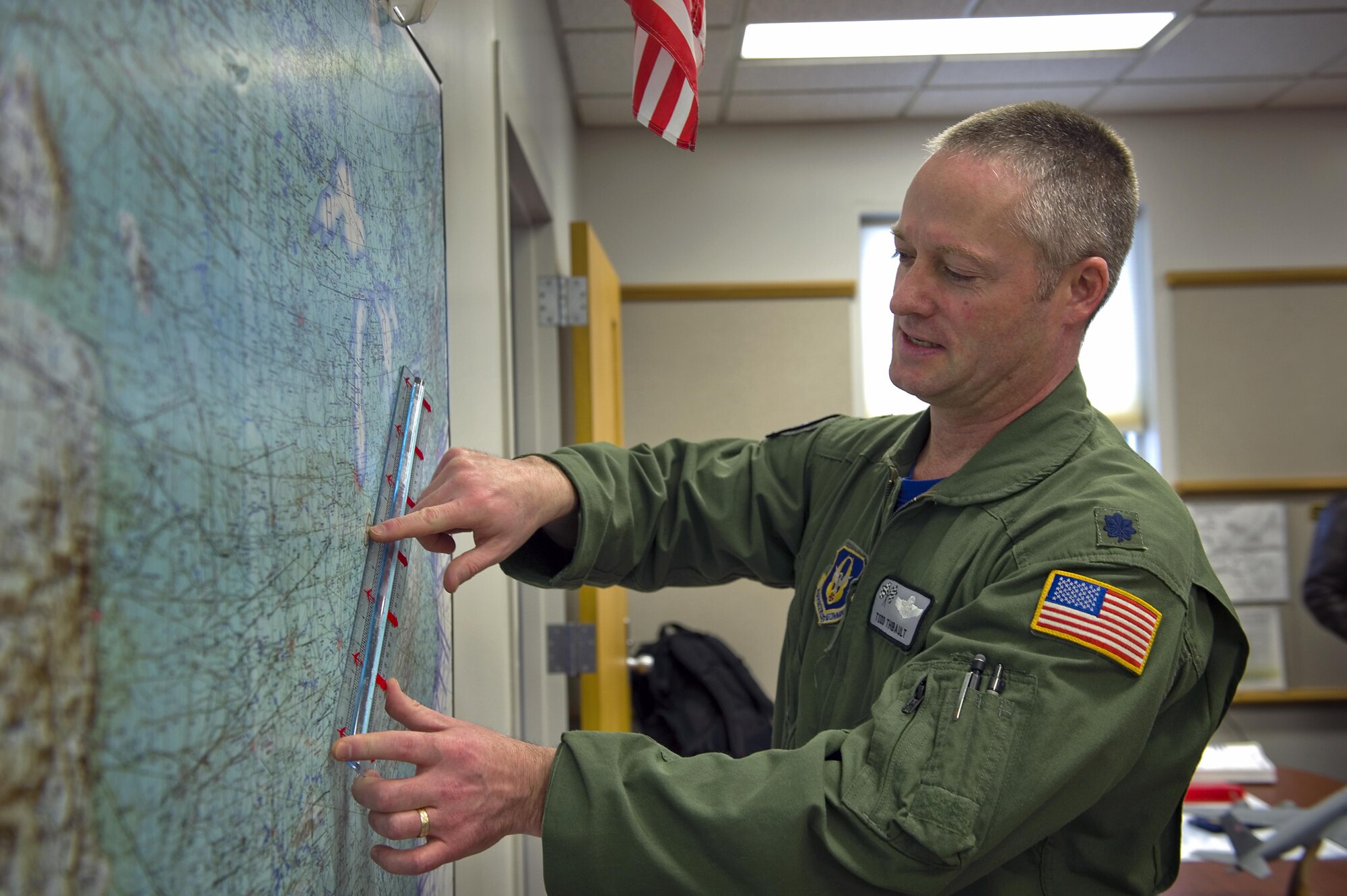 Lt. Col. Todd Thibault, 434th Operations Support Squadron chief of scheduling, points out one of several flight refueling tracks on a map of the United States at Grissom Air Reserve Base, Ind. Jan. 30, 2014. Schedulers with the 434th OSS coordinated nearly 1,300 successful missions here through their detailed planning efforts in 2014 alone. (U.S. Air Force photo/Tech. Sgt. Benjamin Mota)