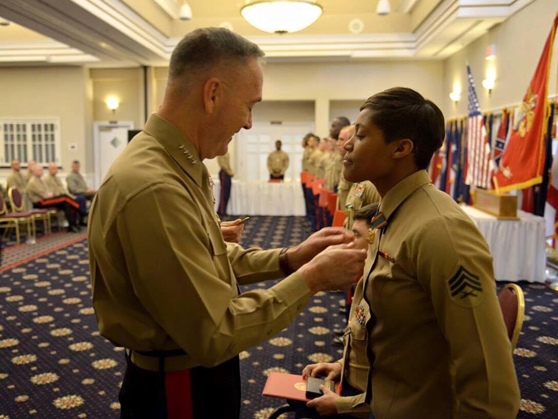 Commandant of the Marine Corps, Gen. Joseph F. Dunford Jr., pins a Navy and Marine Corps Achievement Medal on Sgt. Candice Clark-Thomas in front of other fellow athlete winners, Marine Corps Systems Command and Marine Corps Logistics Base Albany Marines. Clark-Thomas, operations noncommissioned officer, SYSCOM, at MCLB Albany, was named the 2014 Marine Female Athlete of the Year and attended a ceremony at Marine Corps Base Quantico, Virginia, to receive her award.