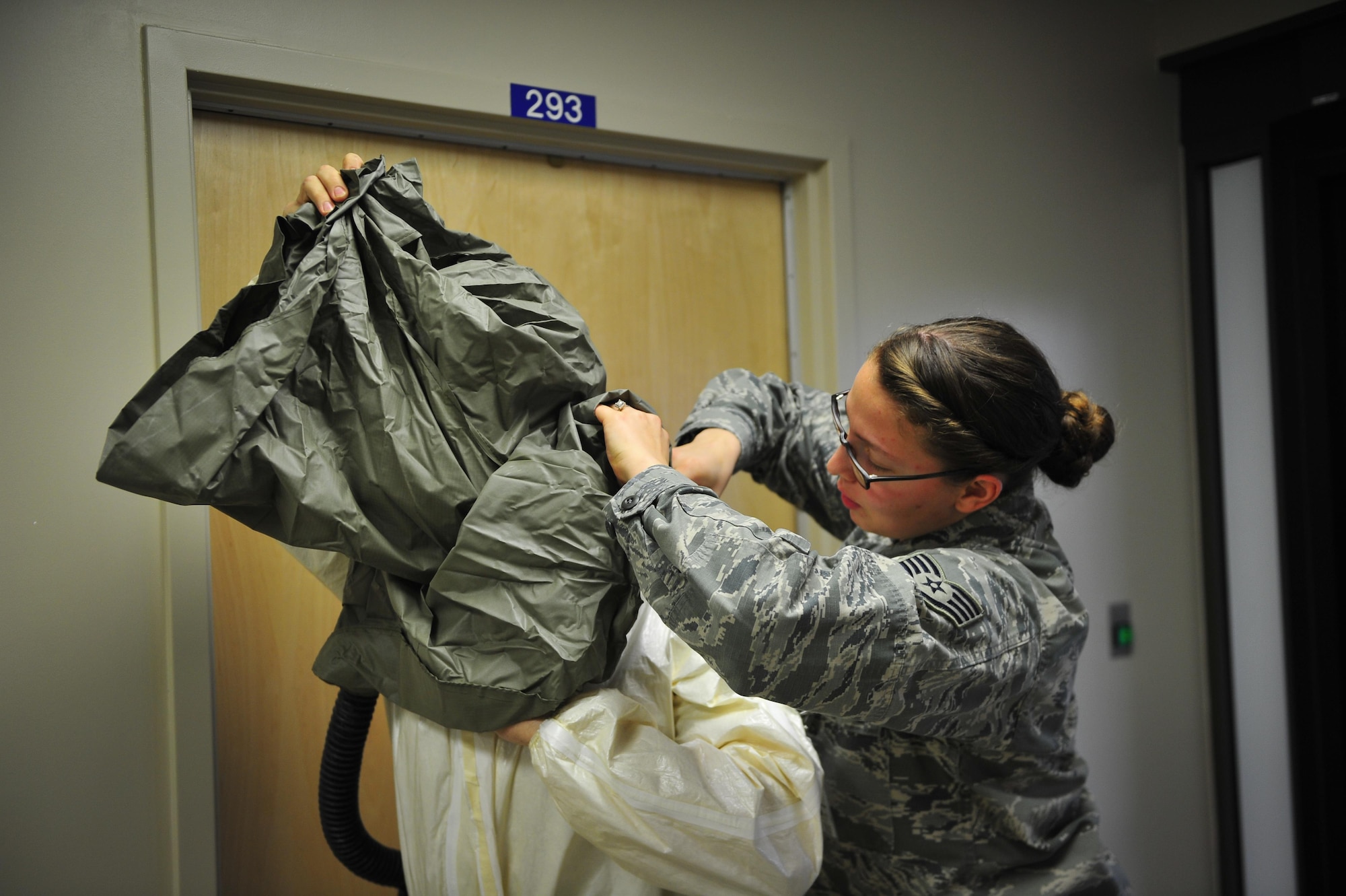 Staff Sgt. Kristina Plunkett, 1st Special Operations Dental Squadron, helps another Airman put on his protective gear during a disease containment exercise at Hurlburt Field, Fla., Feb. 4, 2015. The medical staff focused on the interaction and coordination between multiple units that would be involved in responding to a disease outbreak. (U.S. Air Force photo/Senior Airman Christopher Callaway) 