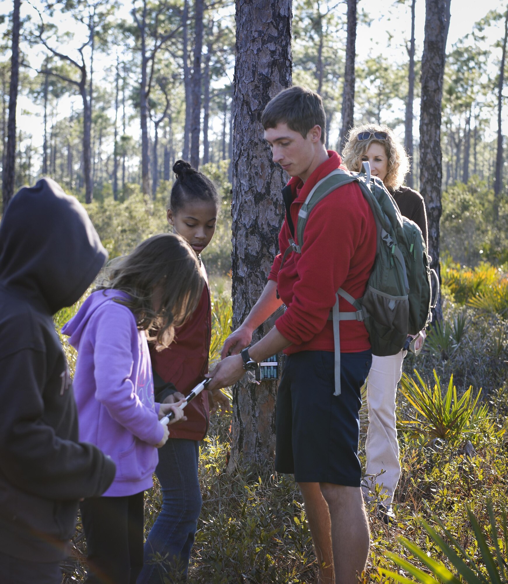 A walking stick is passed to each child to measure the distance between trees at Hurlburt Field, Fla., Feb. 5, 2015. Locations on Hurlburt are randomly selected and mapped by the Smithsonian Institute, to ensure a diversity of habitats for wildlife cameras to capture over the next few months. (U.S. Air Force photo Senior Airman Meagan Schutter/Released)