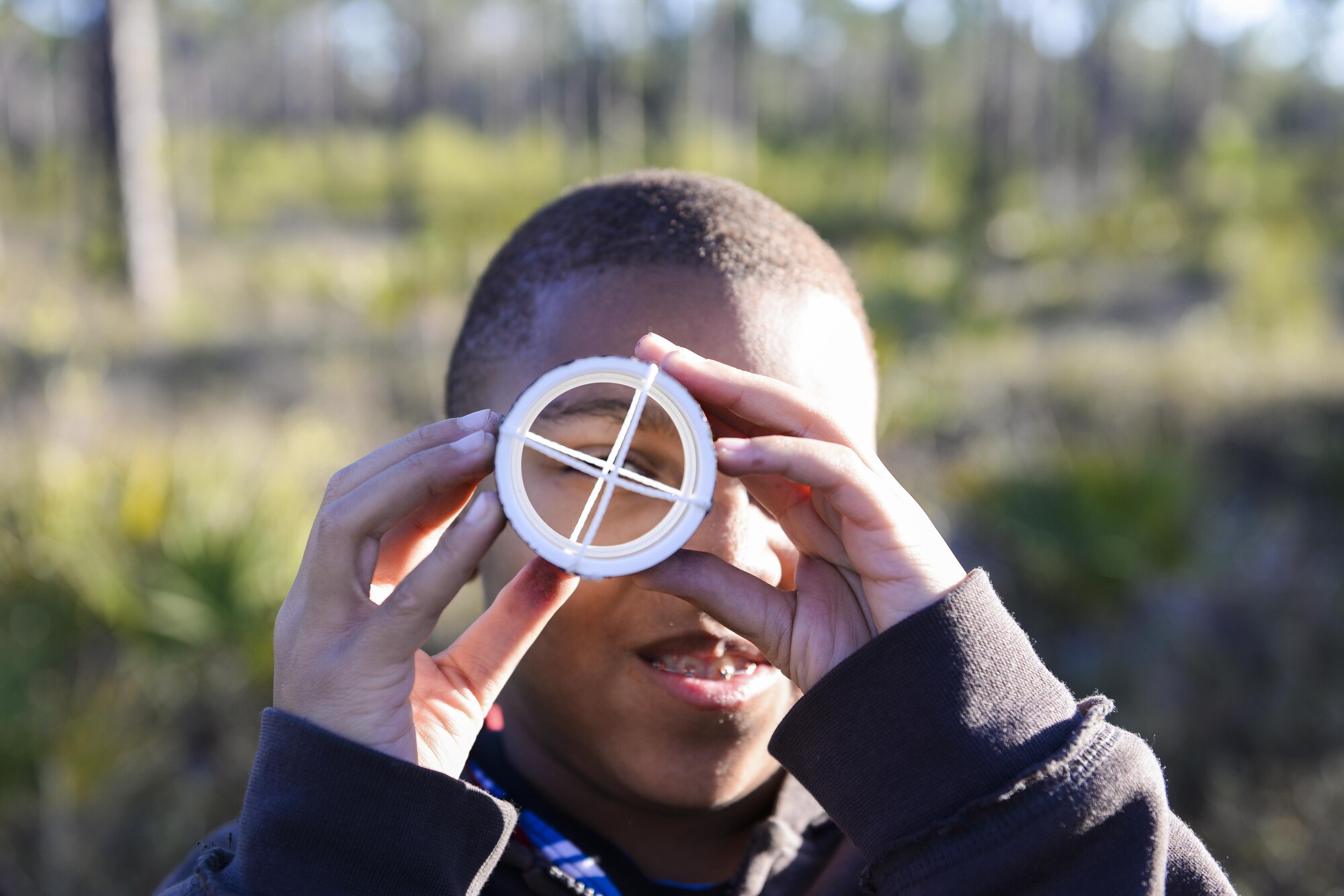A child from the Hurlburt youth group experiments with string and a pipe during a trip to collect deployed cameras at Hurlburt Field, Fla., Feb. 5, 2015. Children on the trip were asked to observe their surroundings, collect data and study the vegetation in the different areas. (U.S. Air Force photo Senior Airman Meagan Schutter/Released)