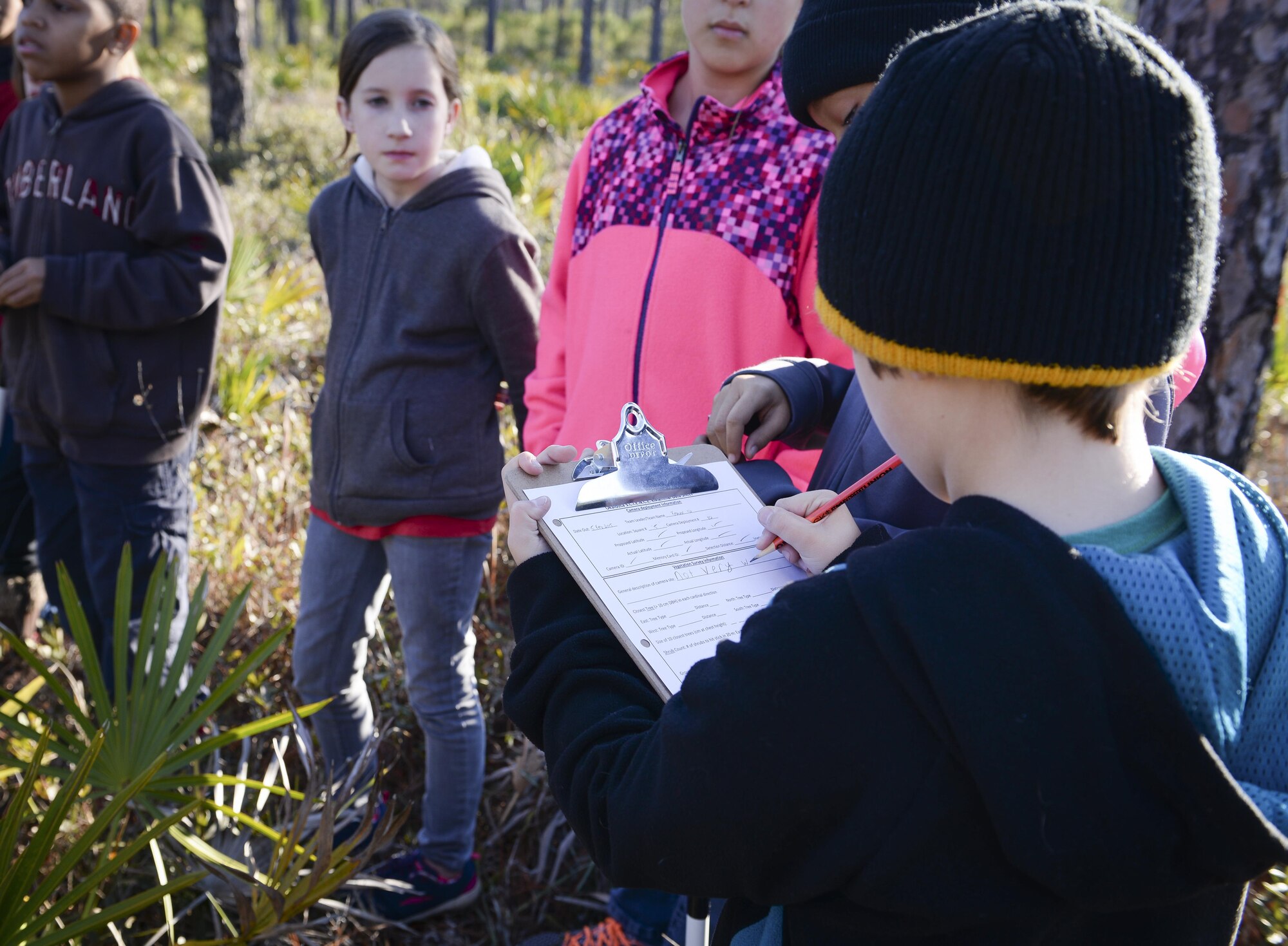 A child from Hurlburt's youth group fills out a list at Hurlburt Field, Fla., Feb. 5, 2015. While searching for the cameras, the children are taught about cardinal directions, vegetation identification, hydrologic indicators, wildlife signs and more. (U.S. Air Force photo Senior Airman Meagan Schutter/Released)