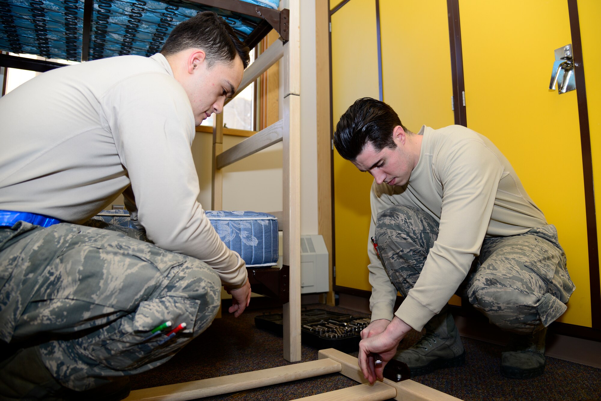 U.S. Air Force Airmen 1st Class Brendan Tarbett and Kurt Brothers, both contingency dorm prep volunteers, tighten screws on a bedframe for future dorm residents Feb. 5, 2014, at Eielson Air Force Base, Alaska. Fourteen Icemen volunteers helped with assembling and moving furniture after a recent renovation. (U.S. Air Force photo by Senior Airman Racheal E. Watson/Released)   