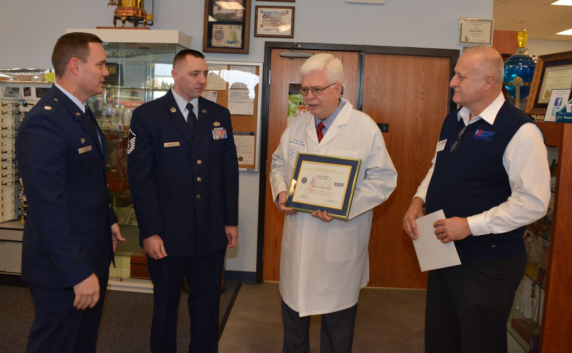 Del City, Okla. employer John Lassiter (middle) of Lassiter Drug Store accepts the Patriot award from the Employer Support of the Guard and Reserve his employee Master Sgt. Zachary Walker (middle left),  Lt. Col. Stan Young, 72nd Aerial Port Squadron commander, (left) and Retired Navy Capt. Gary Foster, Oklahoma ESGR Chairman (right)  (U.S. Air Force Photo/Maj. Jon Quinlan)                                            