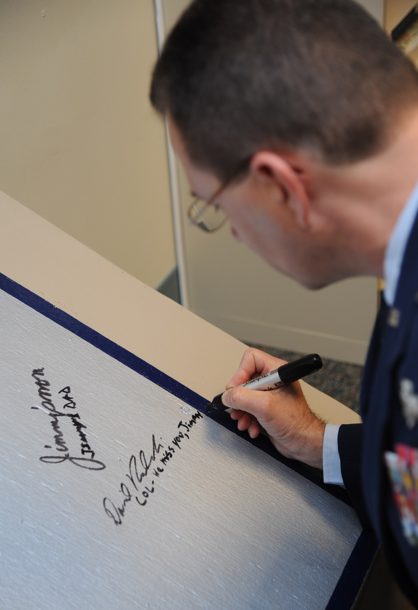 Col. David Radomski, 412th Test Wing vice commander, Edwards Air Force Base, Calif., signs a “T-wall” during a room dedication ceremony to honor Senior Airman James Hansen, Feb. 4, 2015, at Cody Hall, Keesler Air Force Base, Miss.  Hansen was killed in combat in Iraq on Sept. 15, 2010.  He was an airfield management operations coordinator and received his training from the 334th Training Squadron here. (U.S. Air Force photo by Kemberly Groue)