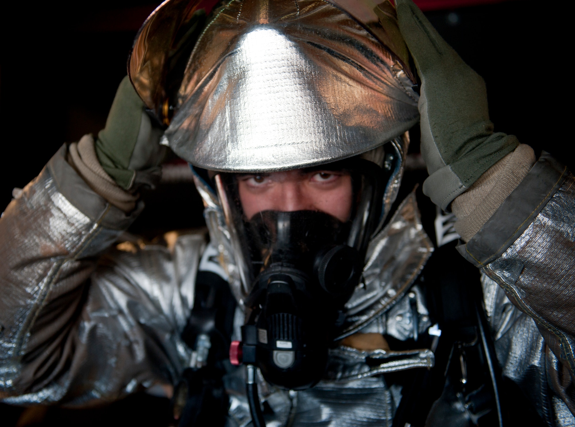 Airman First Class Paul Floyd, 99th Civil Engineer Squadron fire protection apprentice, secures the protective shroud over his helmet during a bunker drill at Nellis Air Force Base, Nev., Jan. 28, 2015. Bunker drills require fire fighters to practice donning their protective gear in an allotted time so they are able to respond quickly to emergencies. (U.S. Air Force photo by Staff Sgt. Victoria Sneed)