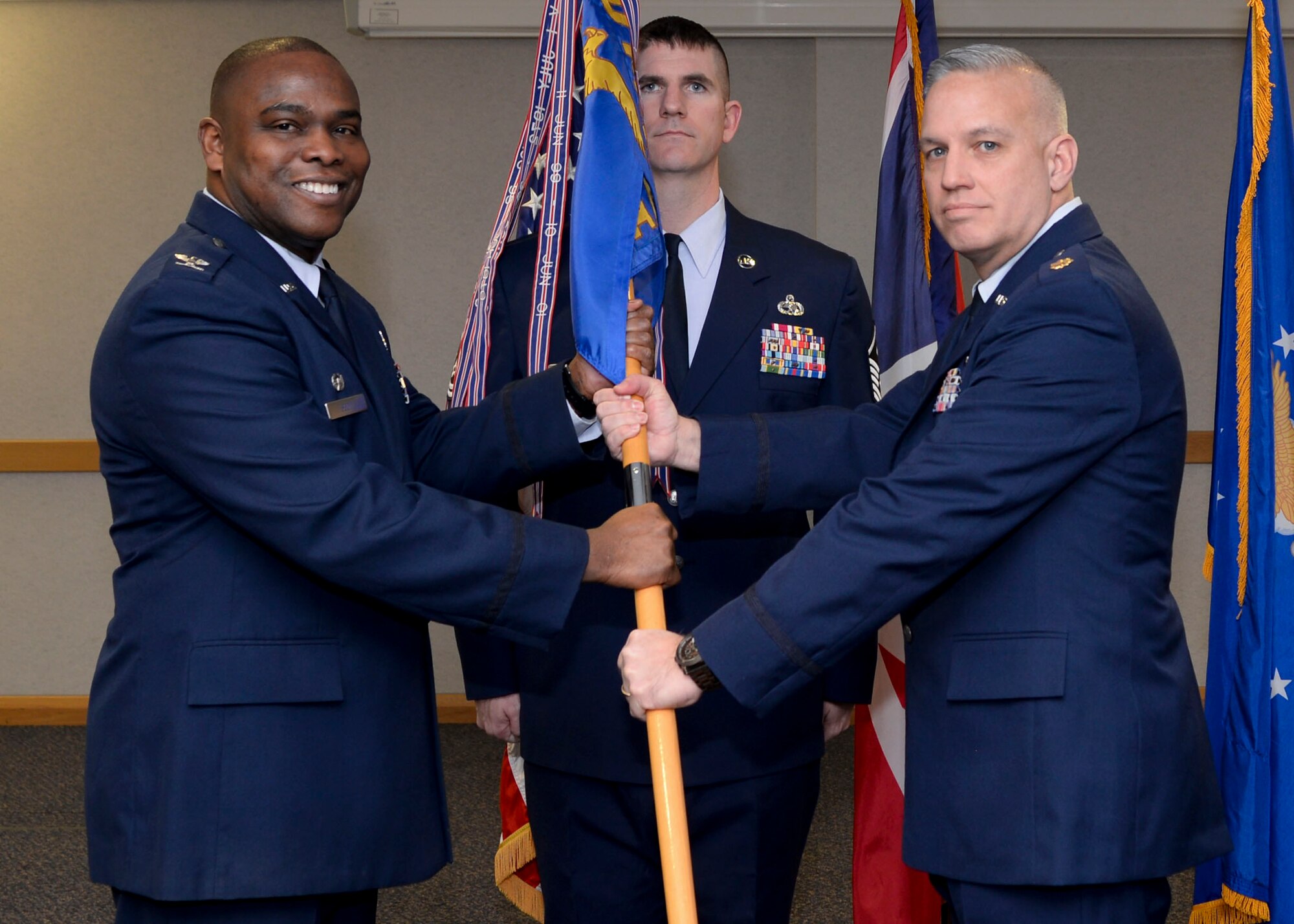 U.S. Air Force Col. Earl S. Scott, left, 100th Maintenance Group commander, presents the guidon to U.S. Air Force Maj. Jeffery Beard, right, newly appointed 100th Aircraft Maintenance Squadron commander, during a change of command ceremony Feb. 5, 2015, on RAF Mildenhall, England.  The passing of the unit guidon during a change of command ceremony is a symbolic representation of passing authority to the incoming commander for all to see. (U.S. Air Force photo by Senior Airman Victoria H. Taylor/Released)