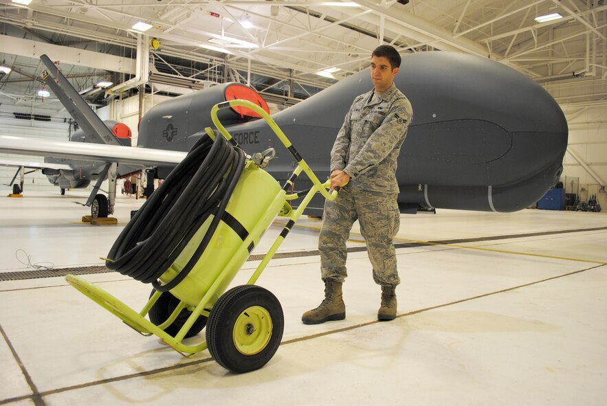 Airman 1st Class Aaron Caldwell, an Advanced Integrated Avionics Systems journeyman with the 69th Maintenance Squadron, positions a Halon fire extinguisher next to a Block 40 RQ-4 Global Hawk inside a hangar on Grand Forks Air Force Base, N.D., Feb. 5, 2015. Halon is a liquefied, compressed gas that stops the spread of fire by chemically disrupting combustion. As a safety precaution, Halon extinguishers are positioned in close proximity to the stationary aircraft in case of a fire emergency. (U.S. Air Force photo/Staff Sgt. Luis Loza Gutierrez)

