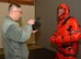 The noncommissioned officer in charge of public affairs at the 932nd Airlift Wing, Tech. Sgt. Christopher Parr, sets his cinematic camera to capture the right lighting conditions indoors as the commander, Col. Karl Goerke, dressed up in the protective 