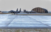 Two F-15E Strike Eagles await instruction from the aircraft control tower before takeoff at Royal Air Force Lakenheath, England, Feb. 4, 2015. The 494th Fighter Squadron participated in a three-day exercise to evaluate their response time to real-world alerts. (U.S. Air Force photo by Airman 1st Class Dawn M. Weber/Released)