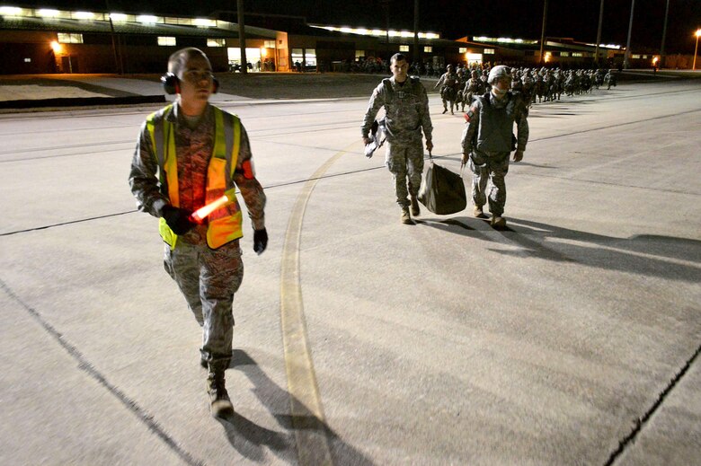 U.S. Air Force Airman 1st Class Mychailjo Nepip, a passenger services agent from the 3rd Aerial Port Squadron, escorts U.S. Army paratroopers from the 2nd Brigade Combat Team, 82nd Airborne Division, onto an U.S. Air Force C-17 Globemaster III transport aircraft from the 437th Airlift Wing, Joint Base Charleston, South Carolina, on Green Ramp, Pope Army Airfield, North Carolina, Jan. 27, 2015, during an Emergency Deployment Readiness Exercise. Five hundred paratroopers were airdropped onto Wright Army Airfield, Fort Stewart, Georgia, from five C-17 transport aircraft 18 hours after notification. As the nucleus of the nation's Global Response Force, the 82nd Airborne Division provides a strategic hedge for combatant commanders with a responsive, agile and operationally significant response force that is flexible in size and composition to accomplish missions anywhere in the world. Air Mobility Command's participation also illustrates the critical partnership between Mobility Air Forces and the U.S. Army by exercising Joint Forcible Entry: the capability of rapidly introducing forces into hostile environments to conduct operations—whether combat or humanitarian support. (U.S. Air Force photo/Marvin Krause)