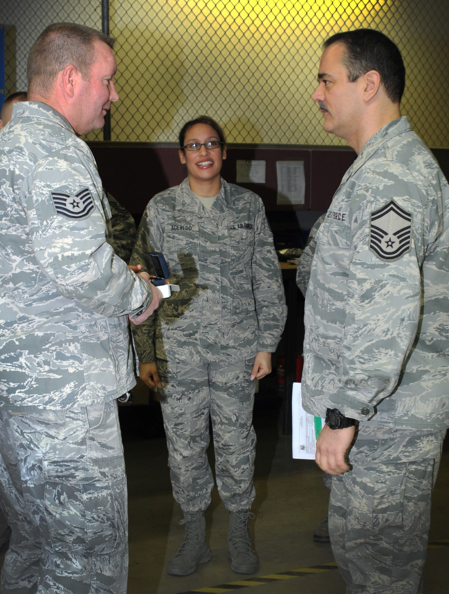 Tech. Sgt. Bill Connolly with the 111th Logistics Readiness Squadron receives a coin from Senior Master Sgt. Gary Lake, 111th LRS, during their commander’s call as Tech. Sgt. Talitacumi Acevedo, 111th Attack Wing Education & Training Office, stands by as a program representative, Feb. 7, 2015, Horsham Air Guard Station, Pa. The coin was given to Connolly as part of a reenlistment recognition program sponsored by the National Guard Bureau (U.S. Air National Guard photo by Tech. Sgt. Andria J. Allmond/Released)
