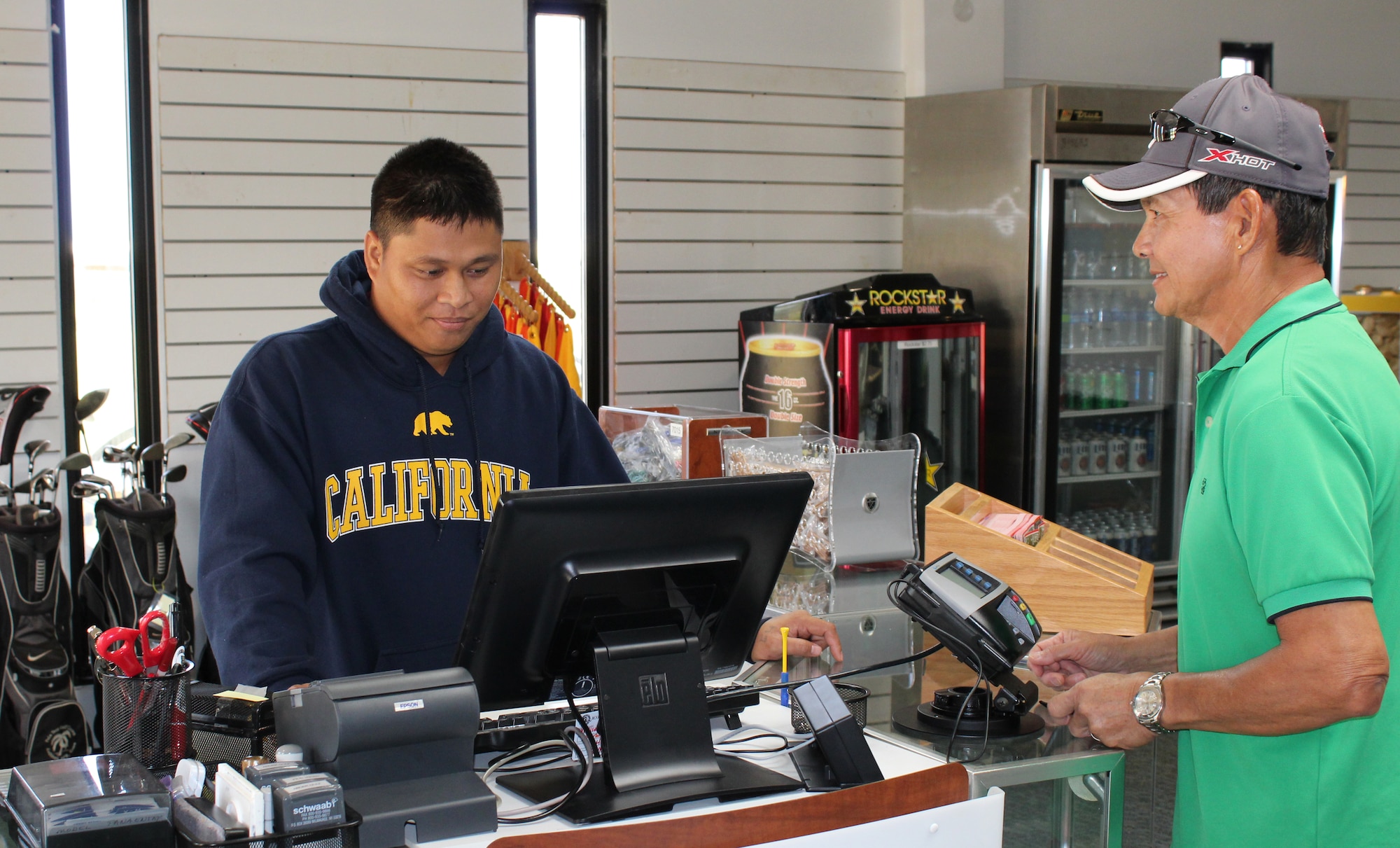 Joel Satur, Palm Tree Golf Course employee, completes a transaction with a customer in the new pro shop Feb. 5, 2015.  Andersen Air Force Base’s Palm Tree Golf Course reopened its golf pro shop in their new location at the Sunrise Conference Center Jan. 31, 2015. (U.S. Air Force photo by 1st Lt. Jessica Clark/Released)