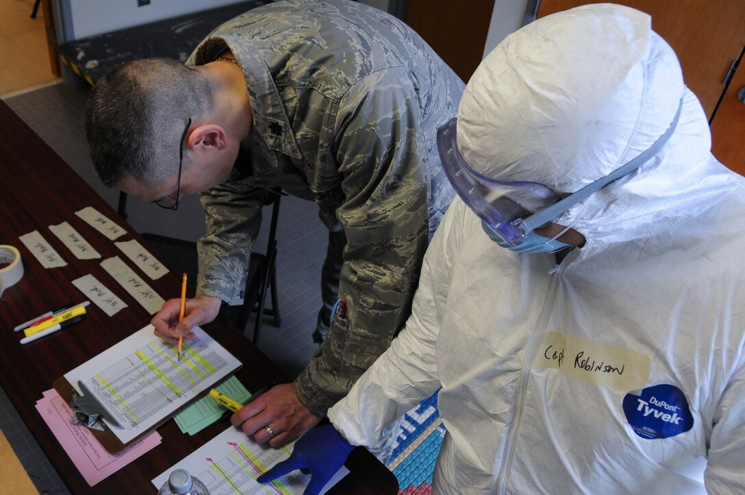 U.S. Air Force Lt. Col. Eric Erickson and Capt. Lisa Robinson with the New Jersey Air National Guard's 177th Fighter Wing Medical Group in Egg Harbor Township, N.J., looks over information on the number of simulated exposures and infections during the base's Disease Containment Exercise on Feb. 8, 2015. The base simulated responding to an Ebola outbreak making sure the base stays mission ready at all times. (U.S. Air National Guard photo by Airman 1st Class Amber Powell)
