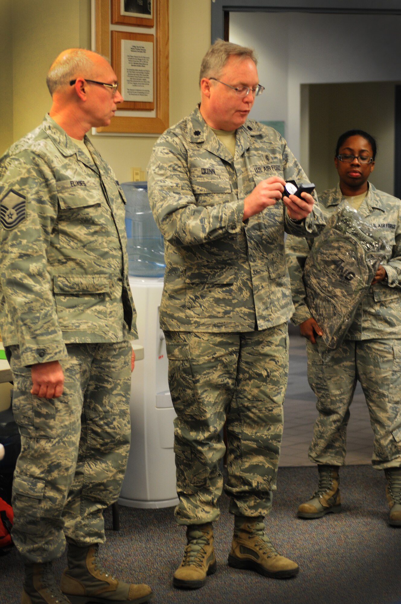 Lt. Col. John Dunn, 111th Attack Wing medical group commander, presents Master Sgt. Christopher Eliades, 111th ATKW medical group, with a coin in recognition of his six-year reenlistment commitment while Staff Sgt. Jovan Tate, 111th ATKW Education and Training Office, stands by to give Eliades a gift that is presented to those who reenlist for the full six years, Feb. 8, 2015, Horsham Air Guard Station, Pa. The new reenlistment recognition program was initiated by the National Guard Bureau with recruiting squadrons and education and training offices, a combined force known as the strength retention team, implementing the program.(U.S. Air National Guard photo by Tech. Sgt. Andria J. Allmond/Release)