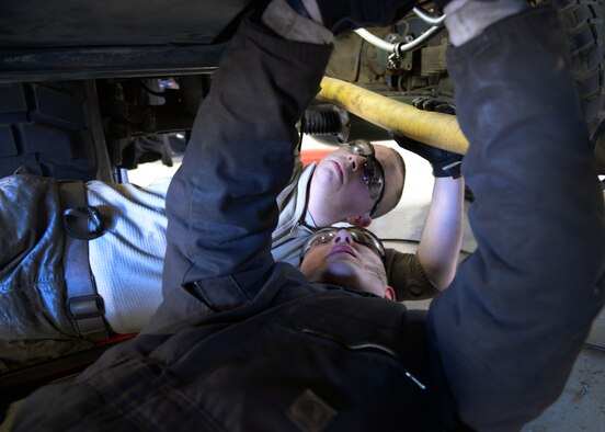 Senior Airman Lloyd Carlyle and Airman 1st Class Joshua Davis, 27th Special Operations Logistics Readiness Squadron fire truck mechanics, work together under an out-of-service M35 fire truck Feb. 5, 2015 at Cannon Air Force Base, N.M. The two are part of a team responsible for repairing the vehicle for Cannon’s civil engineer team. (U.S. Air Force photo/Staff Sgt. Alexxis Mercer)