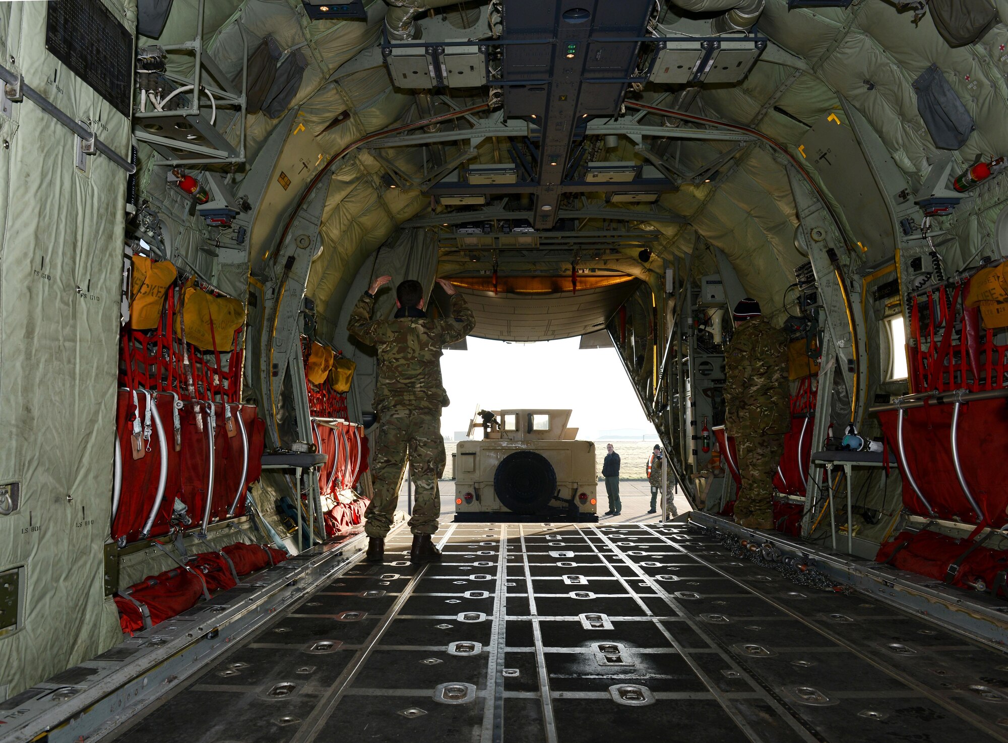 Royal Air Force Senior Aircraftsman Oliver Parsons, Joint Air Delivery trials and evaluations unit member, marshals a Humvee onto a RAF C-130J Super Hercules during training Jan. 20, 2015, on RAF Mildenhall, England. Members of the RAF worked with members of the 352nd Special Operations Support Squadron deployed aircraft ground response element to practice loading and unloading the Humvee in preparation for their upcoming joint training exercise, Emerald Warrior, held at Hurlburt Field, Fla. (U.S. Air Force photo by Senior Airman Kate Maurer/Released)