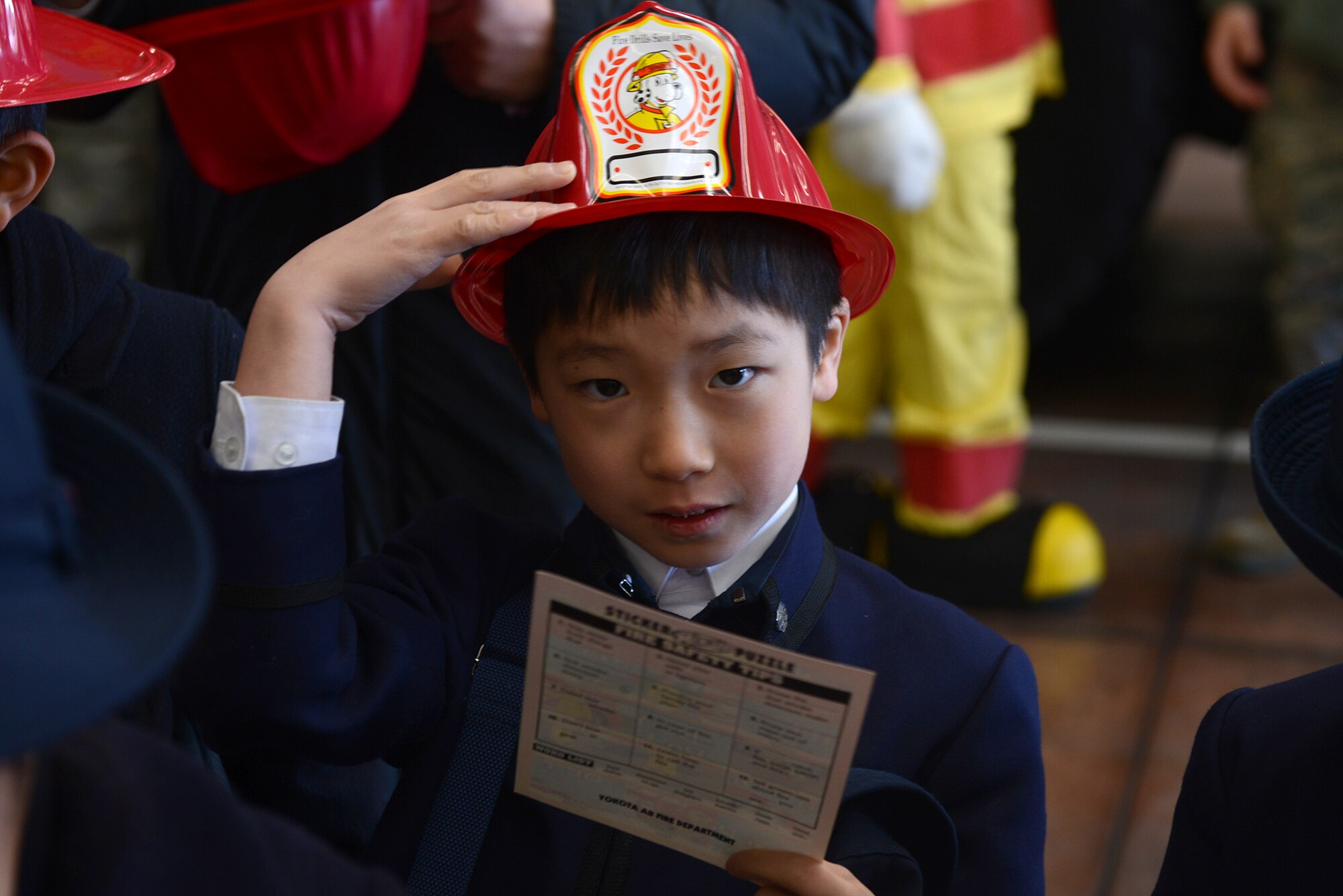 A student from Keimei Gakuen tries on a plastic firefighter helmet at Yokota Air Base, Japan, Feb. 3, 2015. Members of the 374th Civil Engineer Squadron provided the students with free hats and fire-safety pamphlets as part of the base facilities tour. (U.S. Air Force photo by Airman 1st Class David C. Danford/Released)