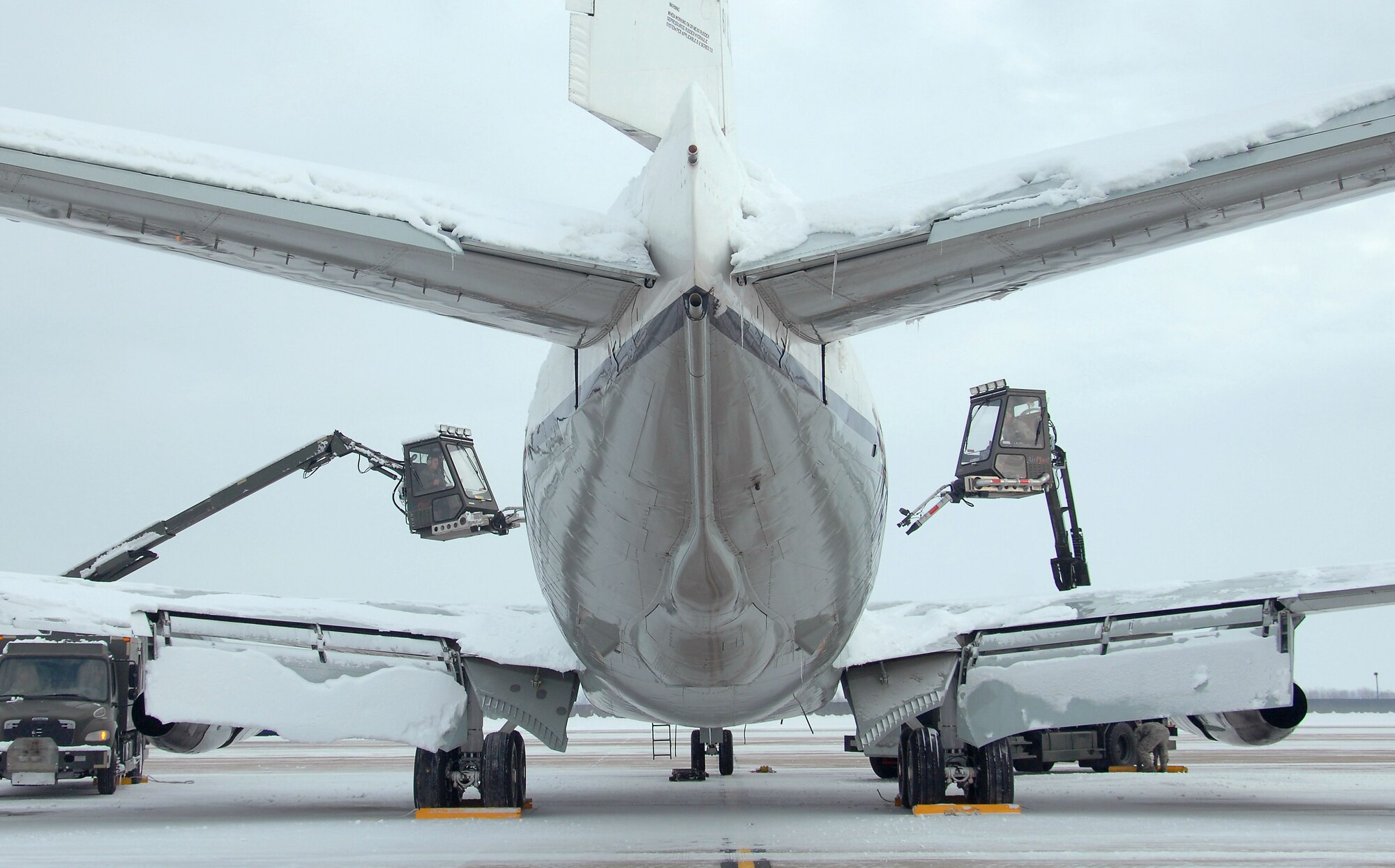 U.S. Air Force Senior Airman Riley Neads, left, and U.S. Air Force Senior Airman Kyle Kindig, right, operate air cannons from deicing trucks to blow snow off of an OC-135 Open Skies aircraft Feb. 3 at Offutt Air Force Base Neb. Additional maintenance time is typically needed during winter operations to heat the aircraft and to remove snow and ice.  Neads and Kindig are assigned to the 83rd Aircraft Maintenance Unit, 55 Aircraft Maintenance Squadron. (U.S. Air Force photo by Delanie Stafford/Released)