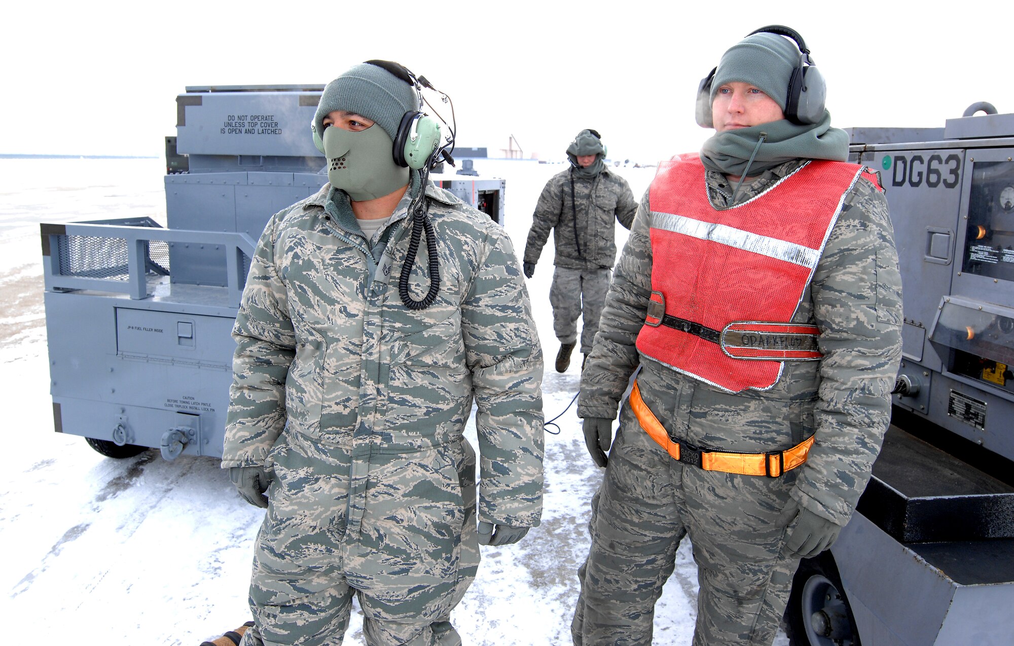 U.S. Air Force Staff Sgt.  Vincent Vasquez, left, U.S. Air Force Airman 1st Class Jordan Scott, background, and U.S. Air Force Senior Airman Jacob Bryson, right, standby while preparing an RC-135 Rivet Joint for launch Feb. 3 at Offutt Air Force Base Neb. Additional maintenance time is typically needed during winter operations to heat aircraft and to remove snow and ice from the aircraft prior to take-off.  They are all crew chiefs assigned to the 83rd Aircraft Maintenance Unit, 55 Aircraft Maintenance Squadron. (U.S. Air Force photo by Delanie Stafford/Released)