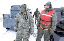 U.S. Air Force Staff Sgt.  Vincent Vasquez, left, U.S. Air Force Airman 1st Class Jordan Scott, background, and U.S. Air Force Senior Airman Jacob Bryson, right, standby while preparing an RC-135 Rivet Joint for launch Feb. 3 at Offutt Air Force Base Neb. Additional maintenance time is typically needed during winter operations to heat aircraft and to remove snow and ice from the aircraft prior to take-off.  They are all crew chiefs assigned to the 83rd Aircraft Maintenance Unit, 55 Aircraft Maintenance Squadron. (U.S. Air Force photo by Delanie Stafford/Released)